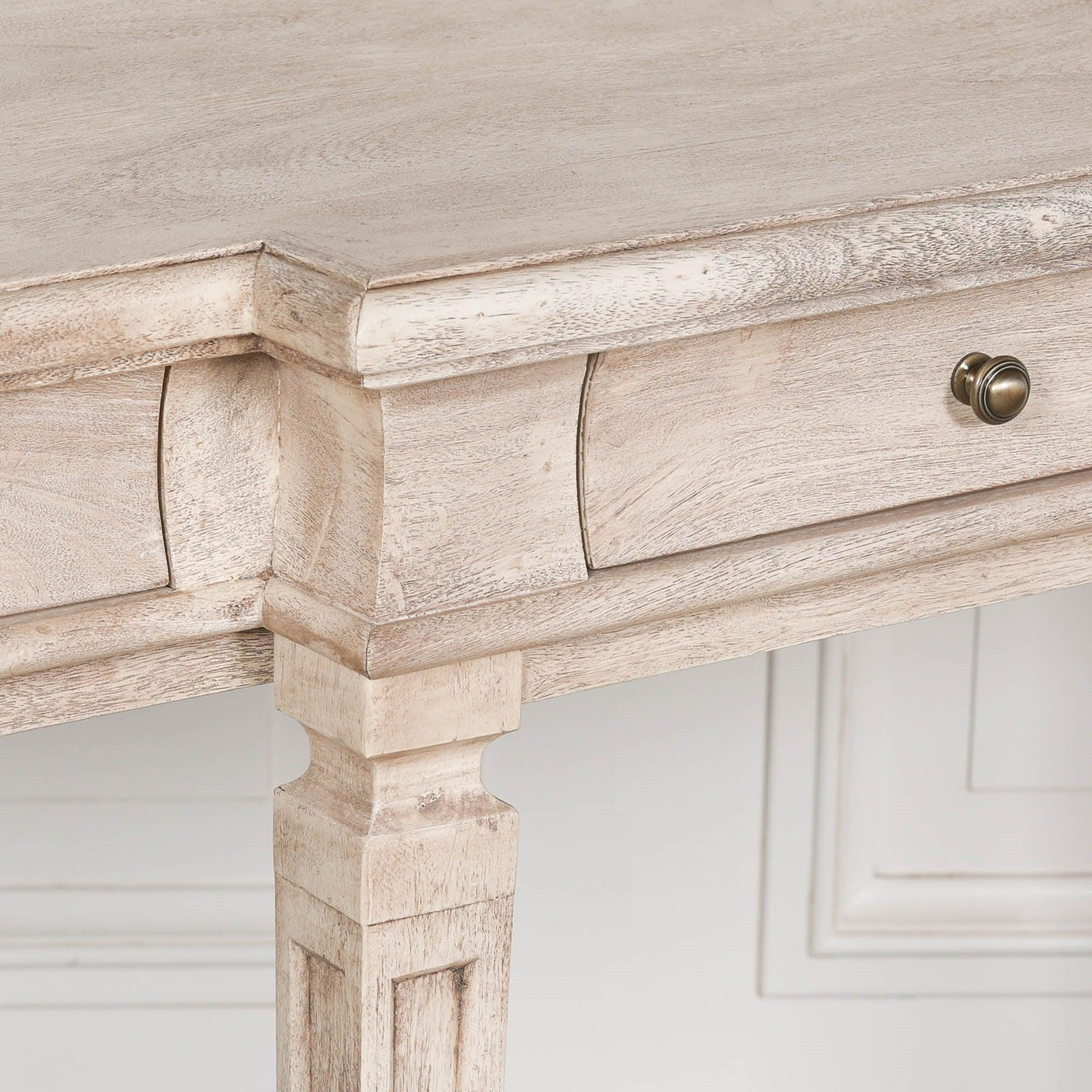Distressed wood console table with drawer and brass knob, close-up of leg and top corner