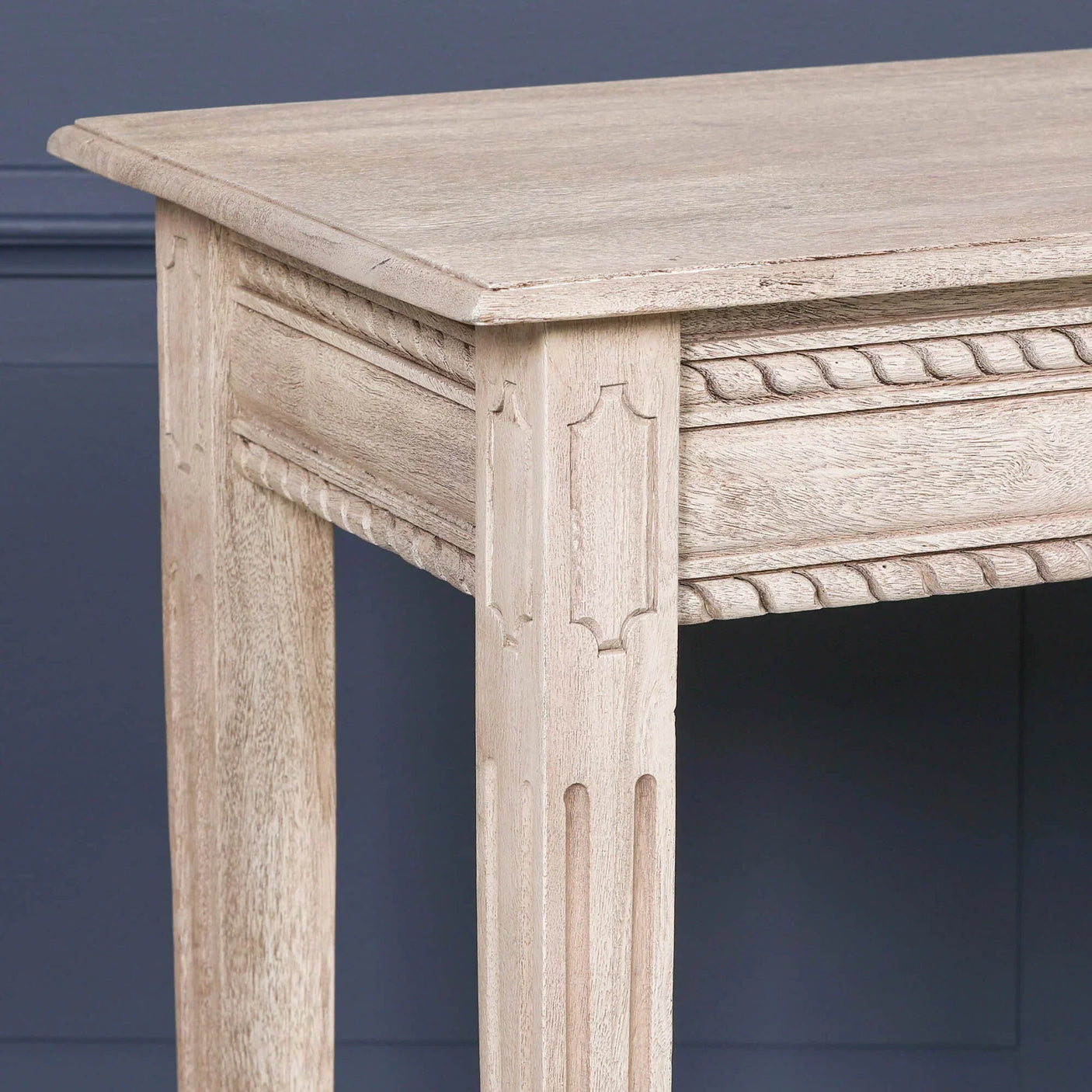 Light wood console table corner with carved detailing and textured finish