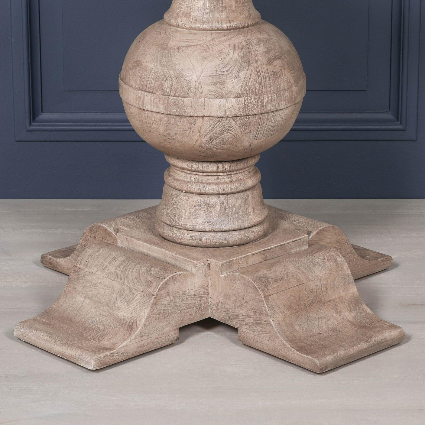 Natural oak dining table base with curved pedestal design on wood floor