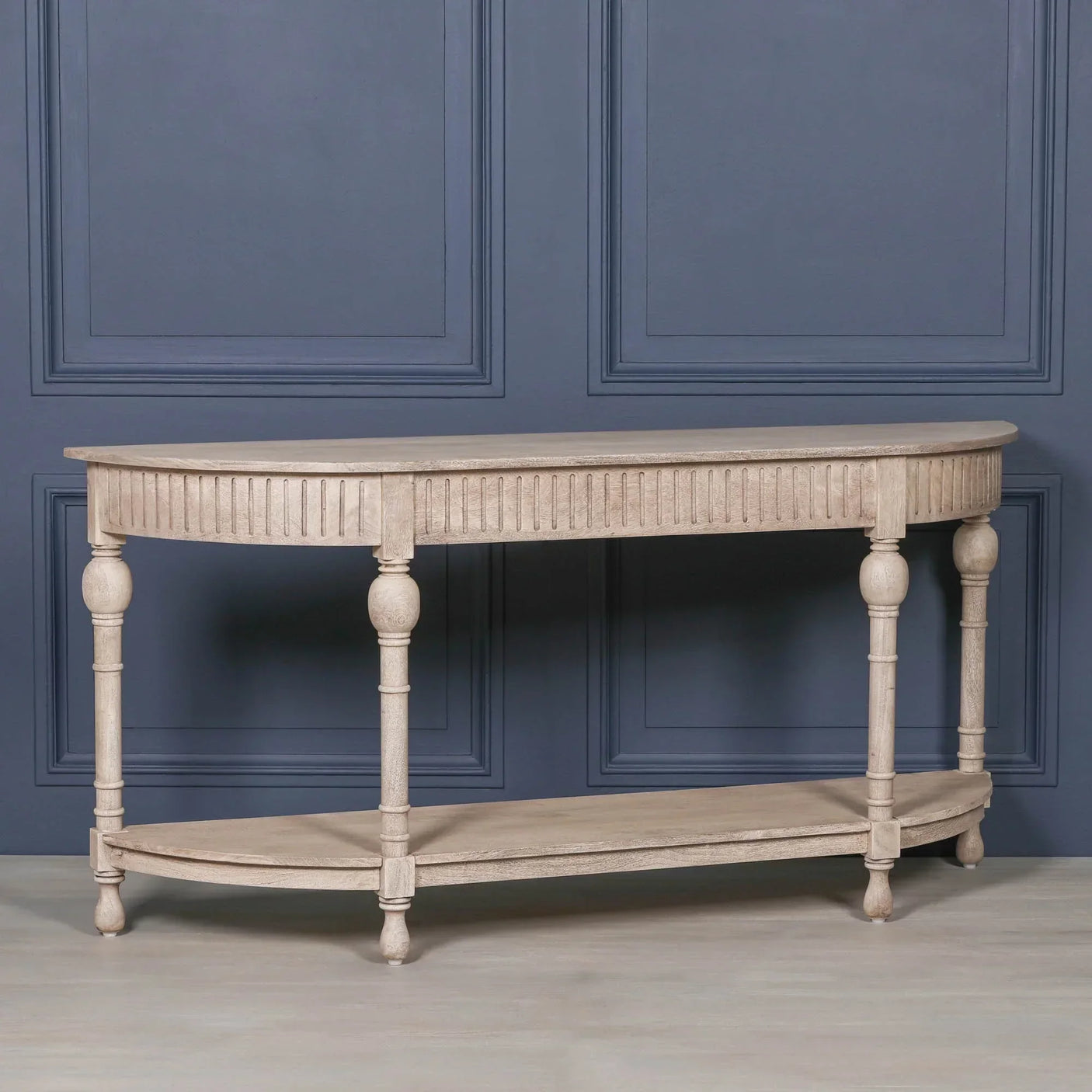 Light wood console table with fluted apron and lower shelf against blue paneled wall