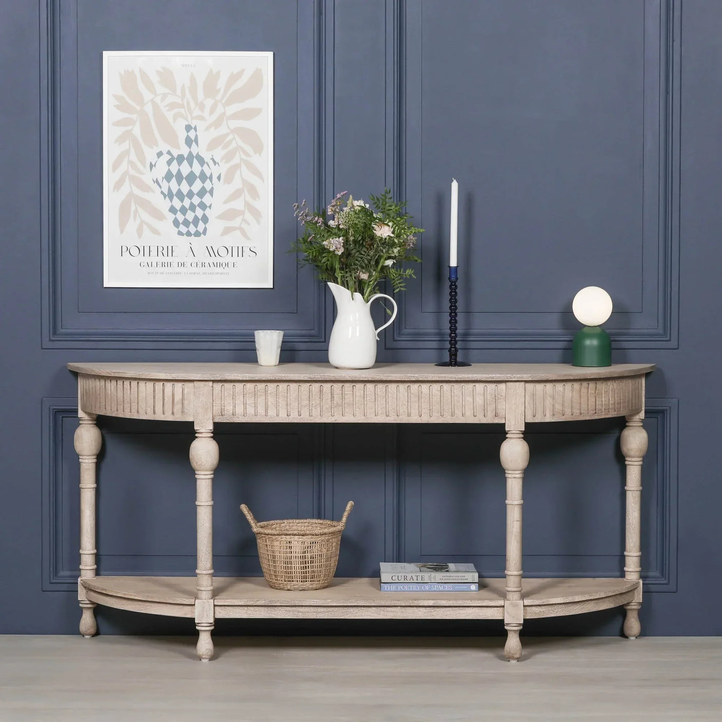 Wooden console table with fluted detail, shelf, and decorative accessories against navy wall
