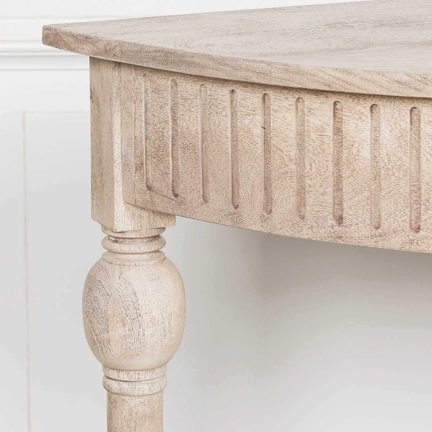 Light wood dining table corner with carved leg and grooved apron detail