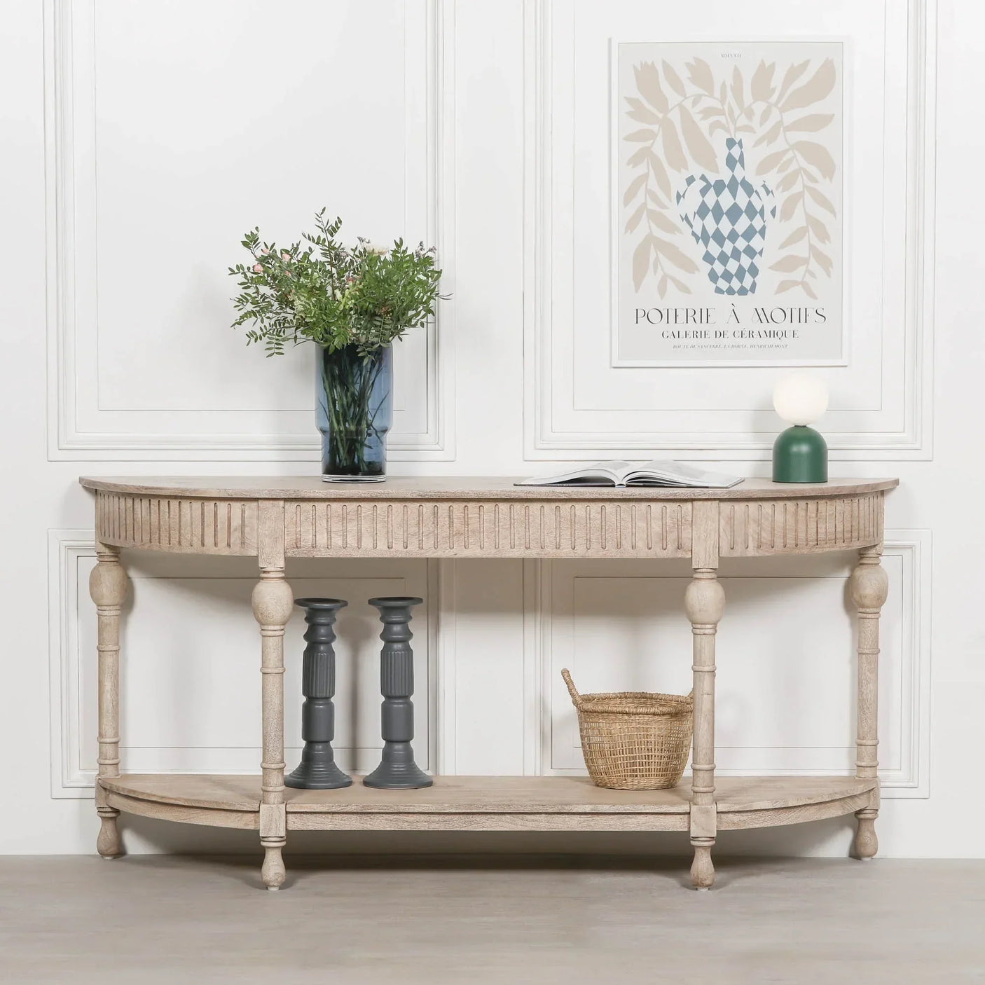 Light wood console table with carved legs, open shelf, and decorative accessories