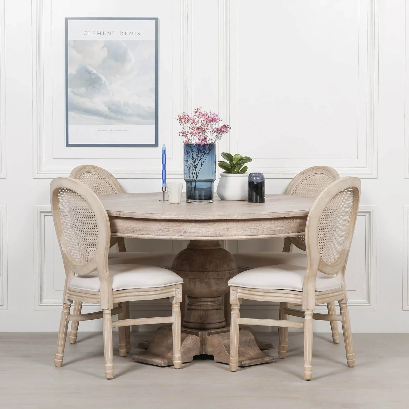 Round wooden dining table with pedestal base and four rattan back chairs
