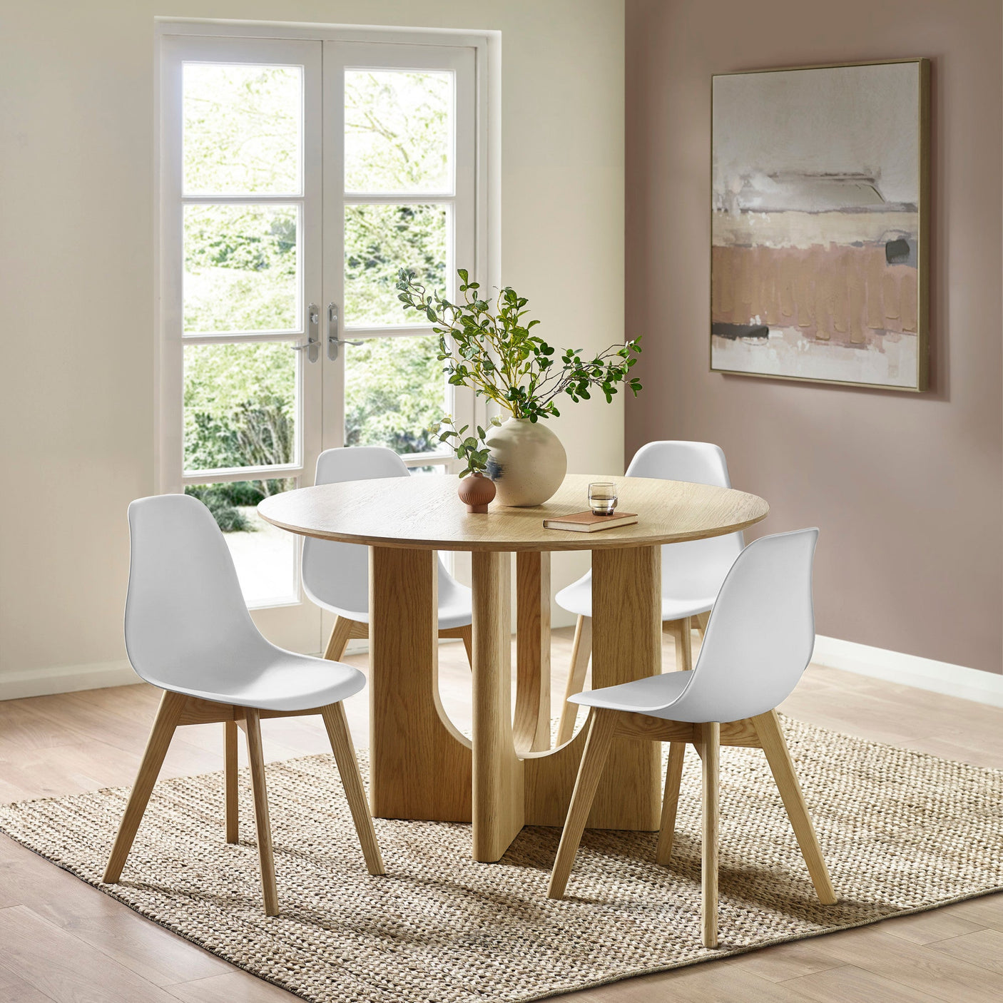 Close-up of white dining chair with light wood legs on woven rug near round oak table