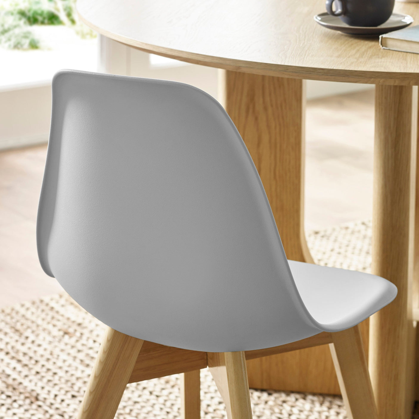 Close-up rear view of grey chair in dining room setting, showing smooth plastic backrest