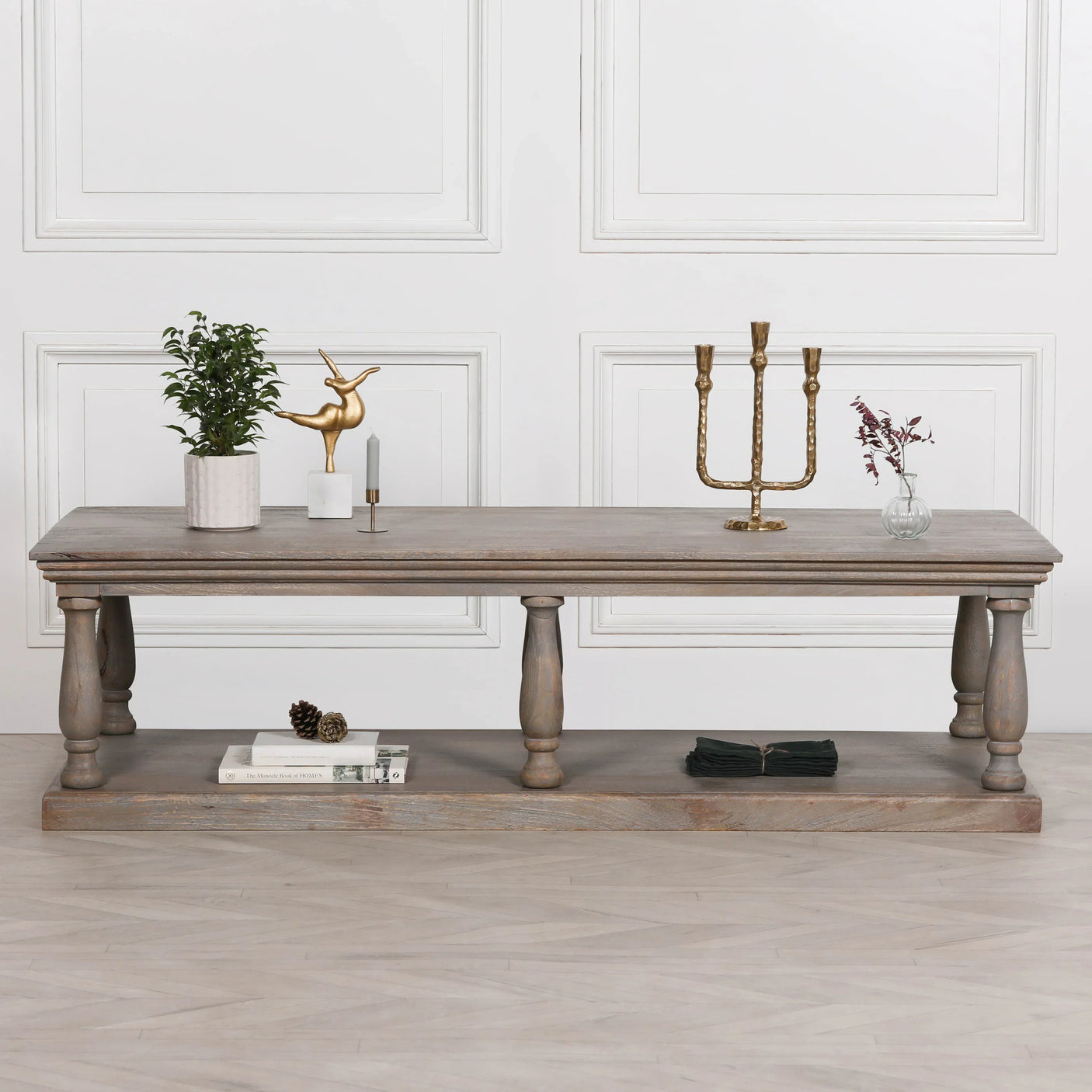 Rustic wooden coffee table with shelf, decorative items and books, set against white wall