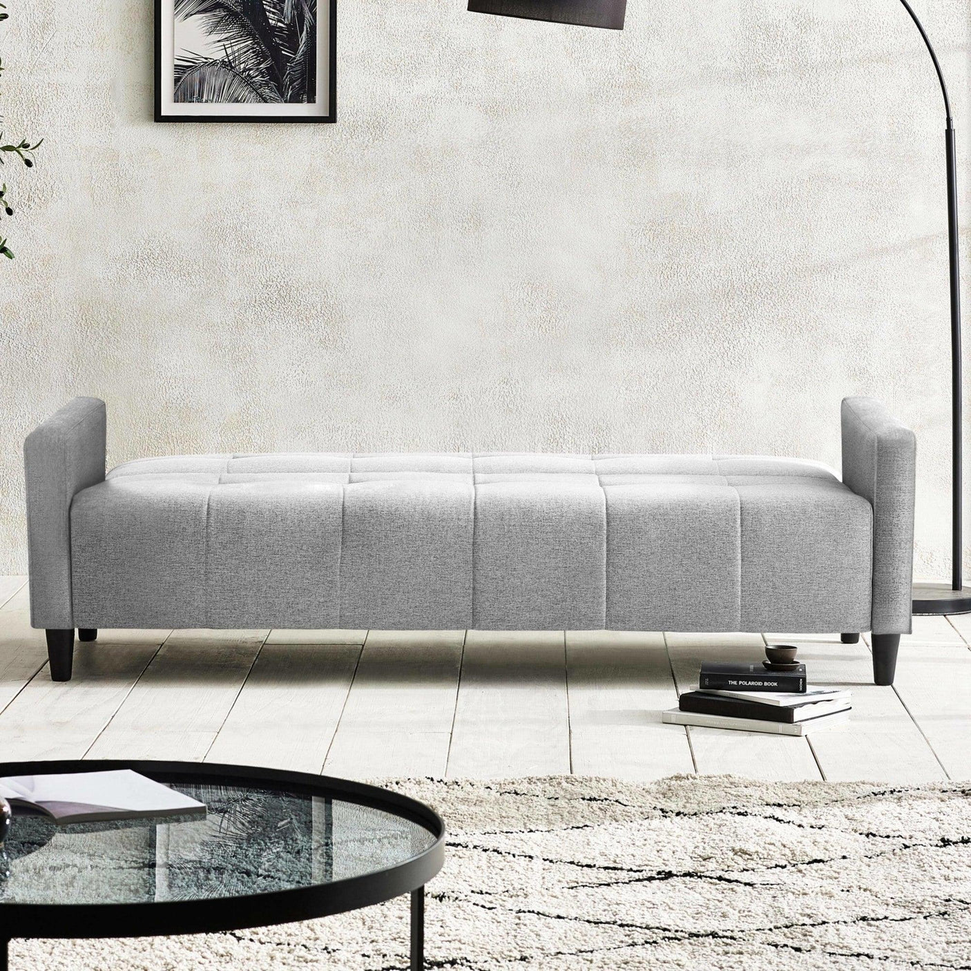 Light grey upholstered bench seat with low arms, set on wooden legs in a modern living room