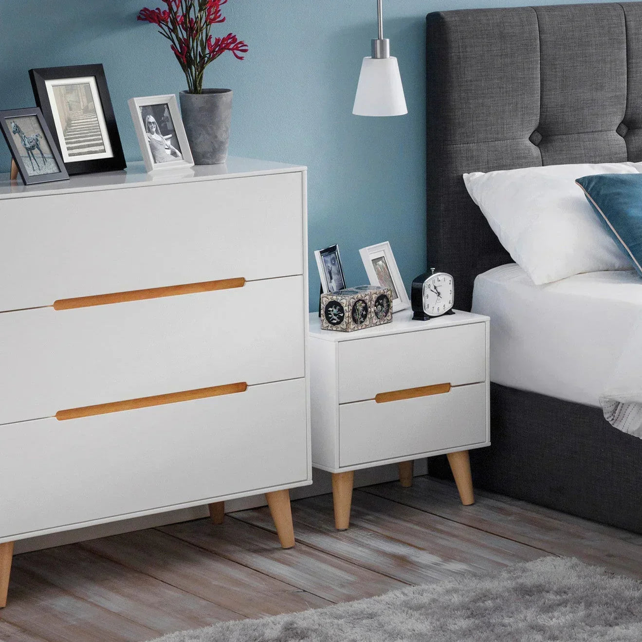 White three drawer chest with wood handles beside matching bedside table in modern bedroom