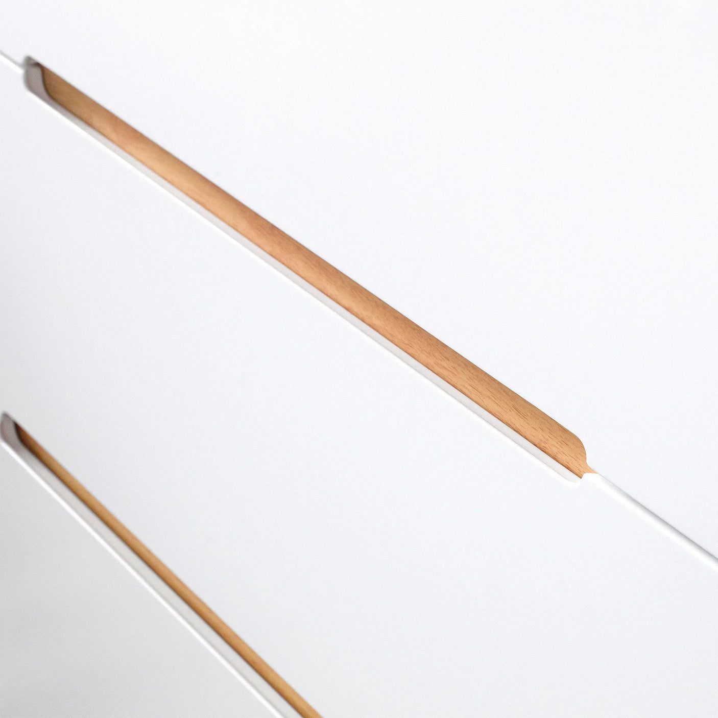 Closeup of white chest of drawers with natural wood handles