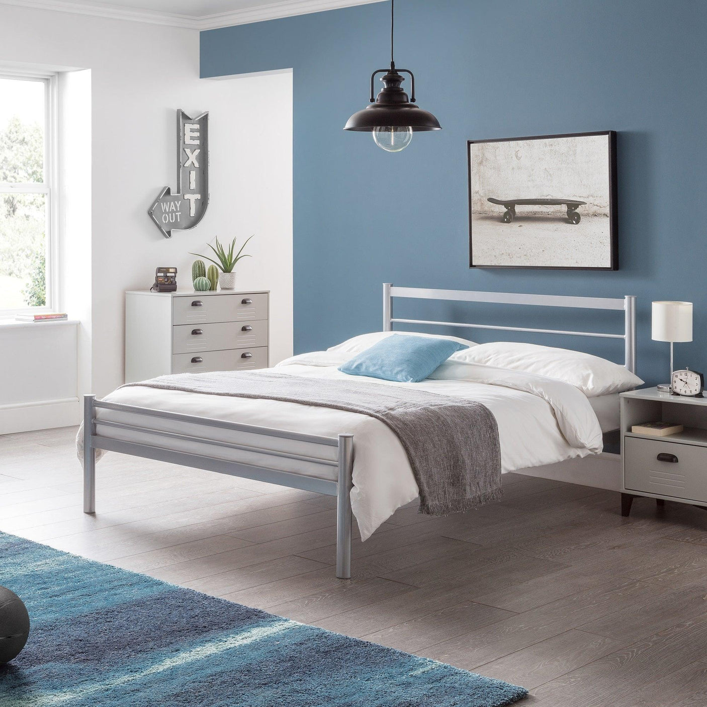 Silver metal double bed with white bedding in modern bedroom with blue accent wall