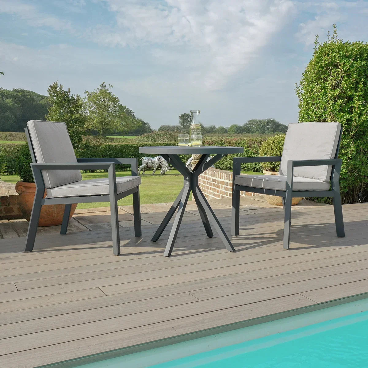 Aluminium outdoor bistro set with two grey cushioned chairs and round table by pool