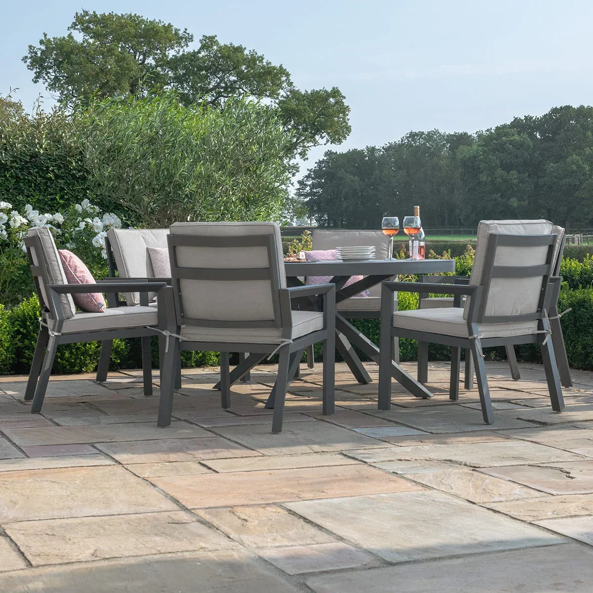 Grey aluminium garden dining set with cushioned chairs on stone patio, outdoor setting
