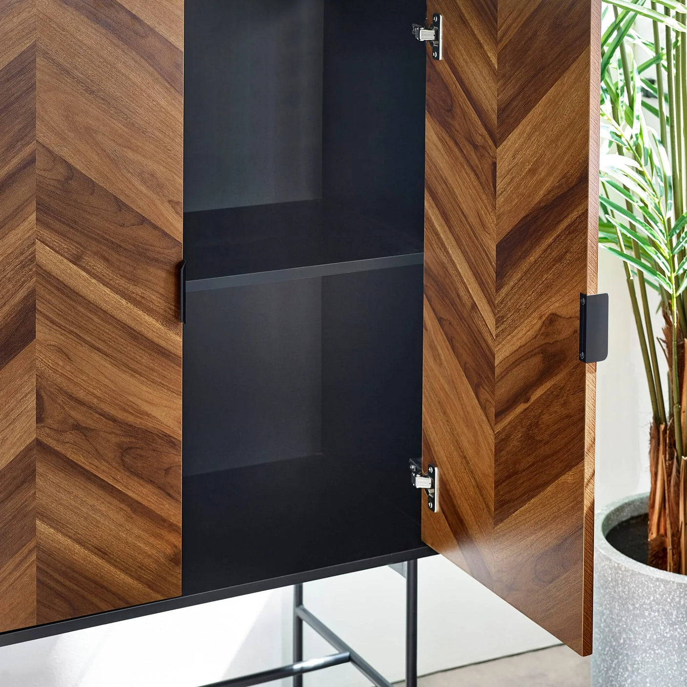 Chevron wood storage cabinet with open doors and black metal shelving