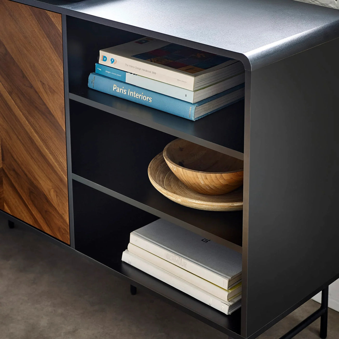 Black sideboard with open shelves, wood detail, books, and wooden bowls on display