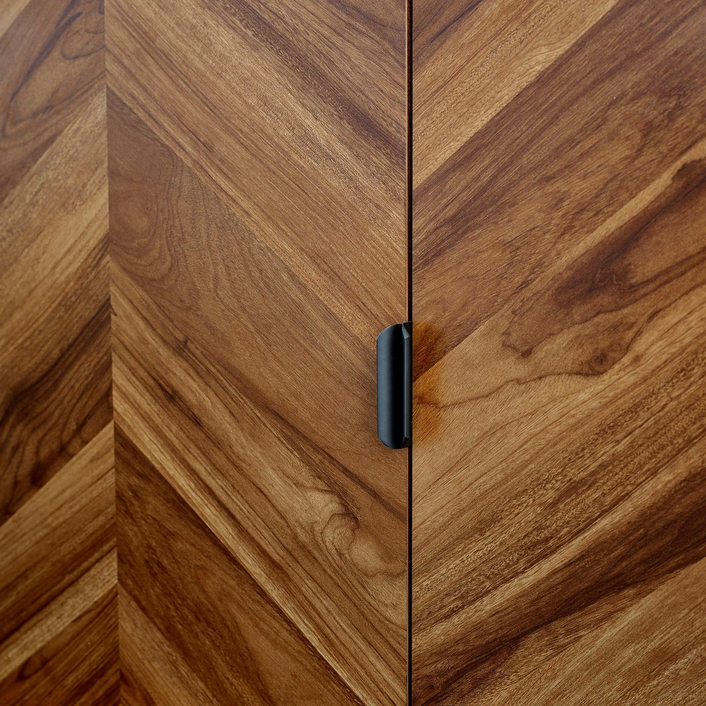 Chevron pattern wood cabinet door with black metal handle close-up