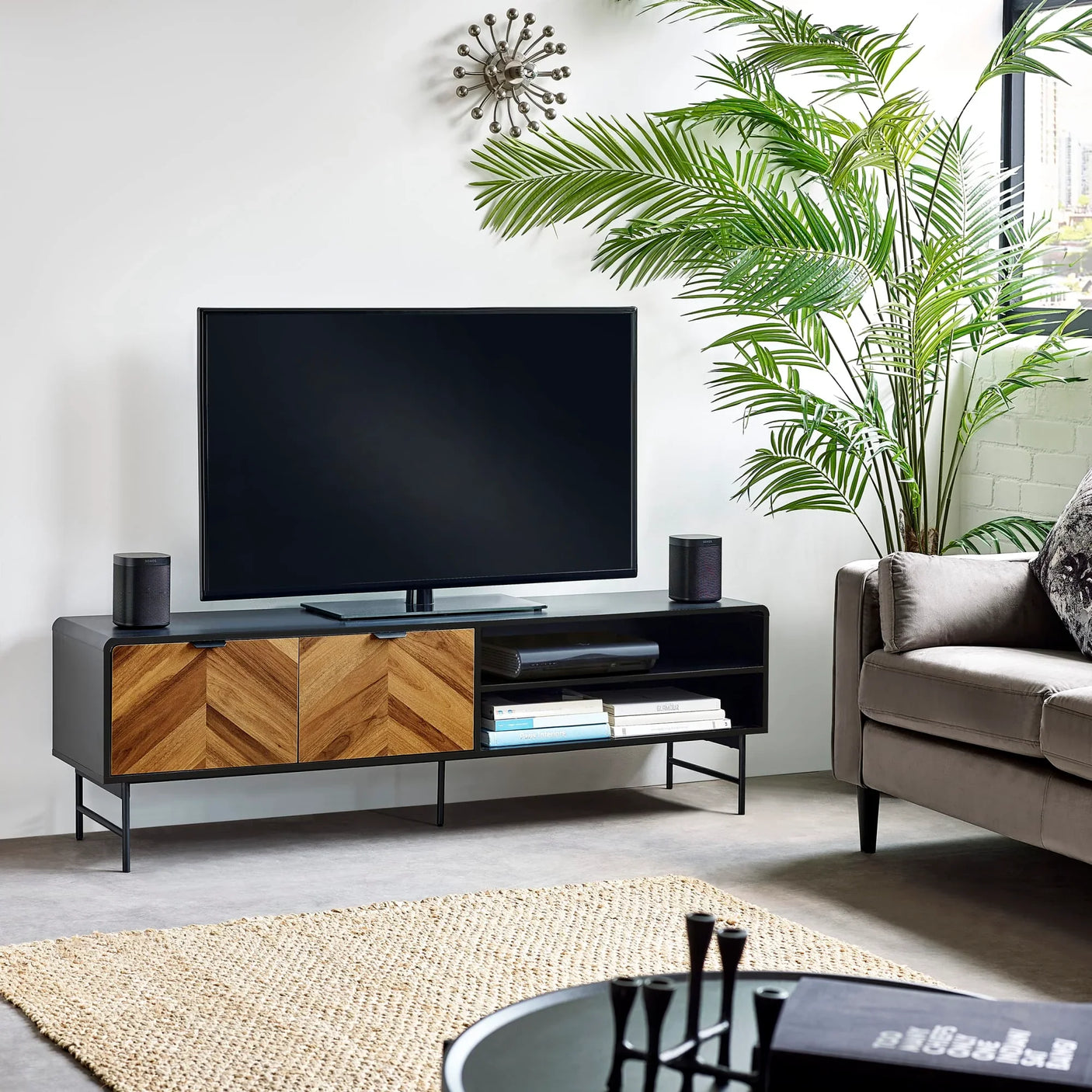 Modern TV stand with wood chevron doors, black frame, and open shelves in living room