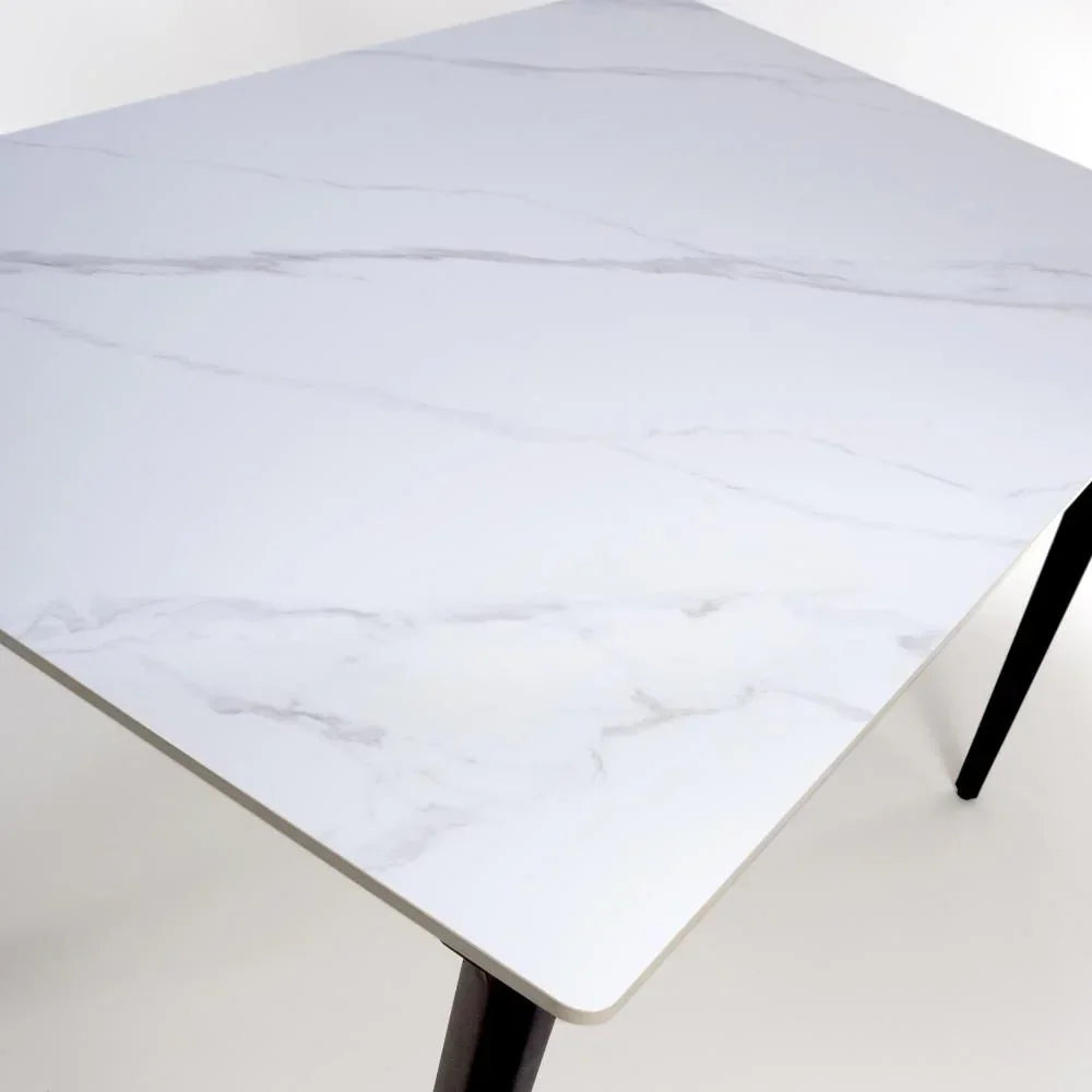 White marble effect dining table top with black legs, close-up showing corner detail