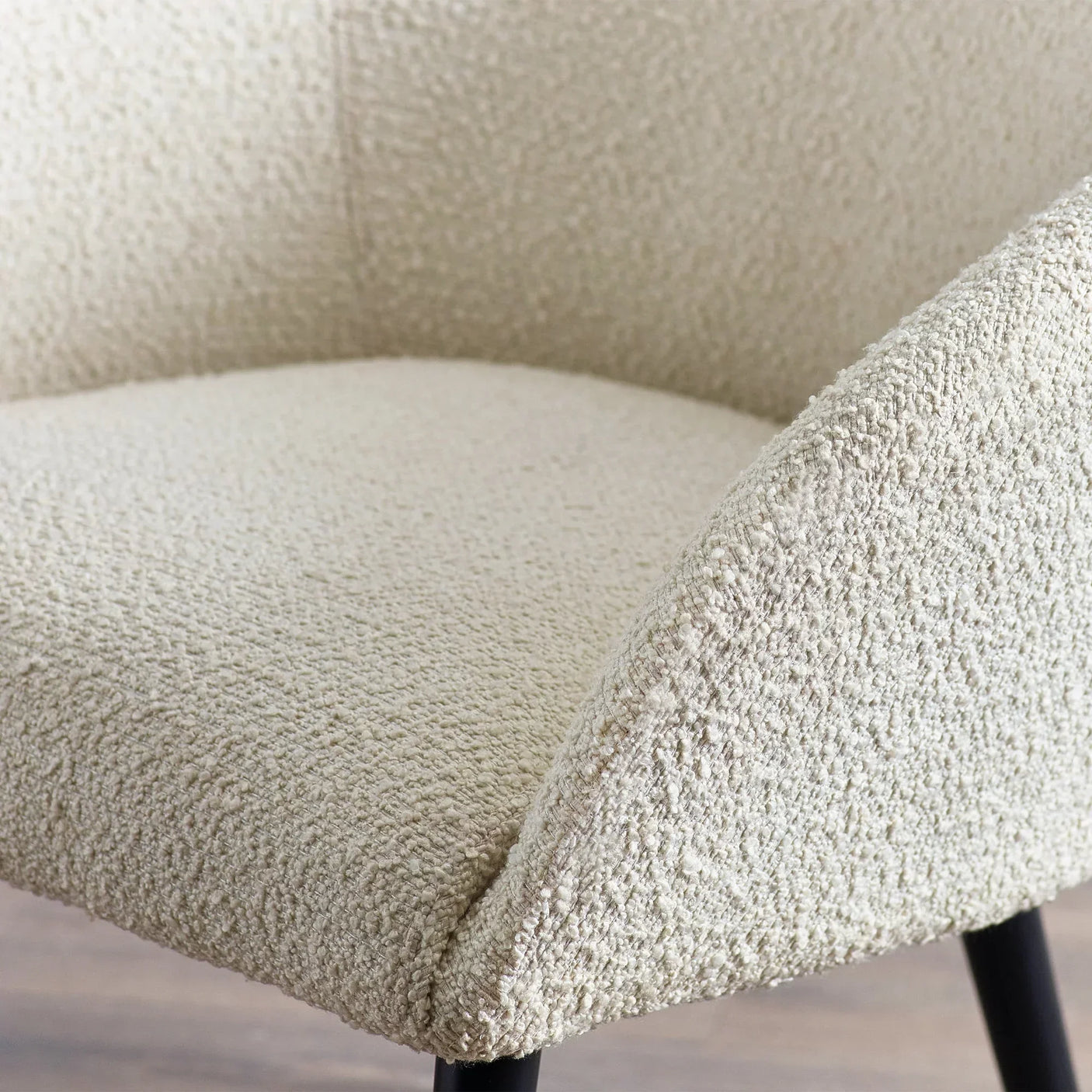 Close-up of boucle accent chair with cream upholstery and black legs