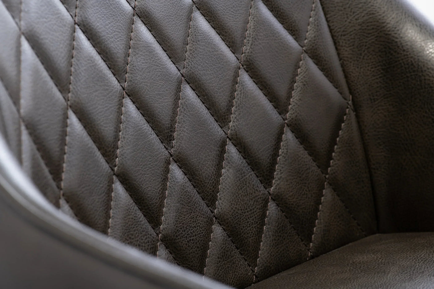 Closeup of diamond-stitched faux leather chair upholstery in dark brown