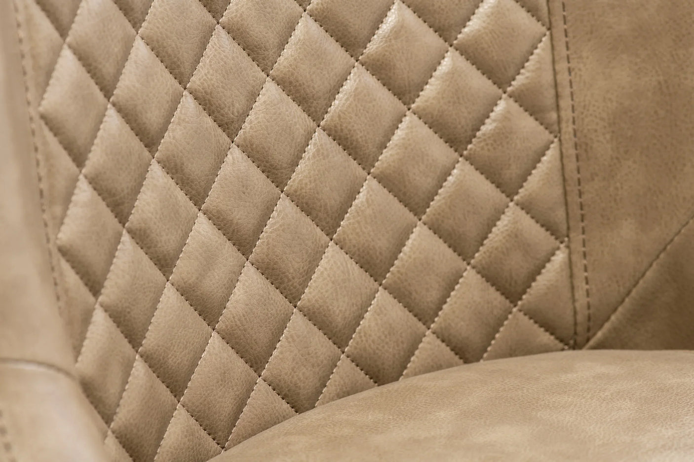 Diamond-stitched tan leather chair back with close-up detail of upholstery texture