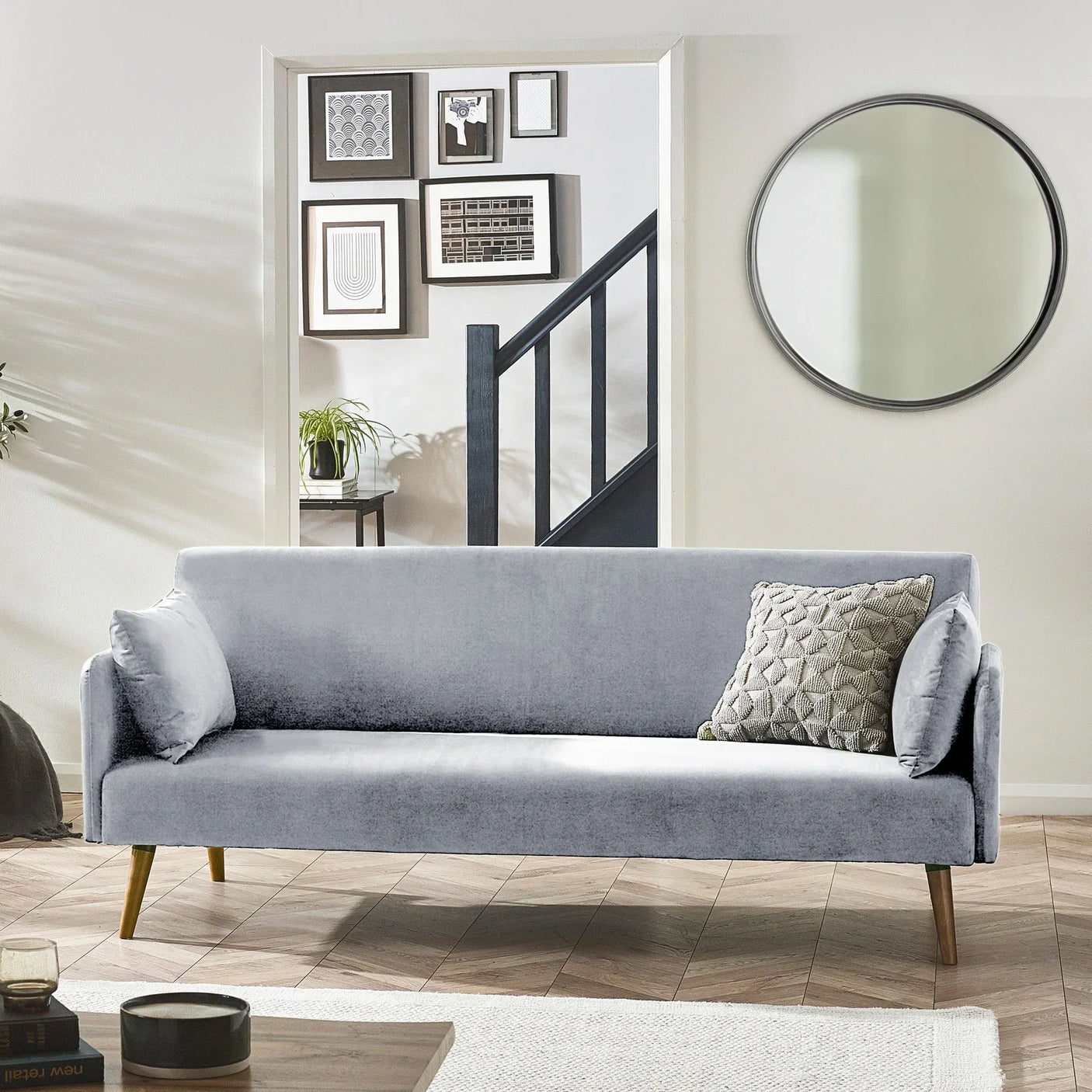 Grey sofa bed with wooden legs in modern living room with wall art and round mirror