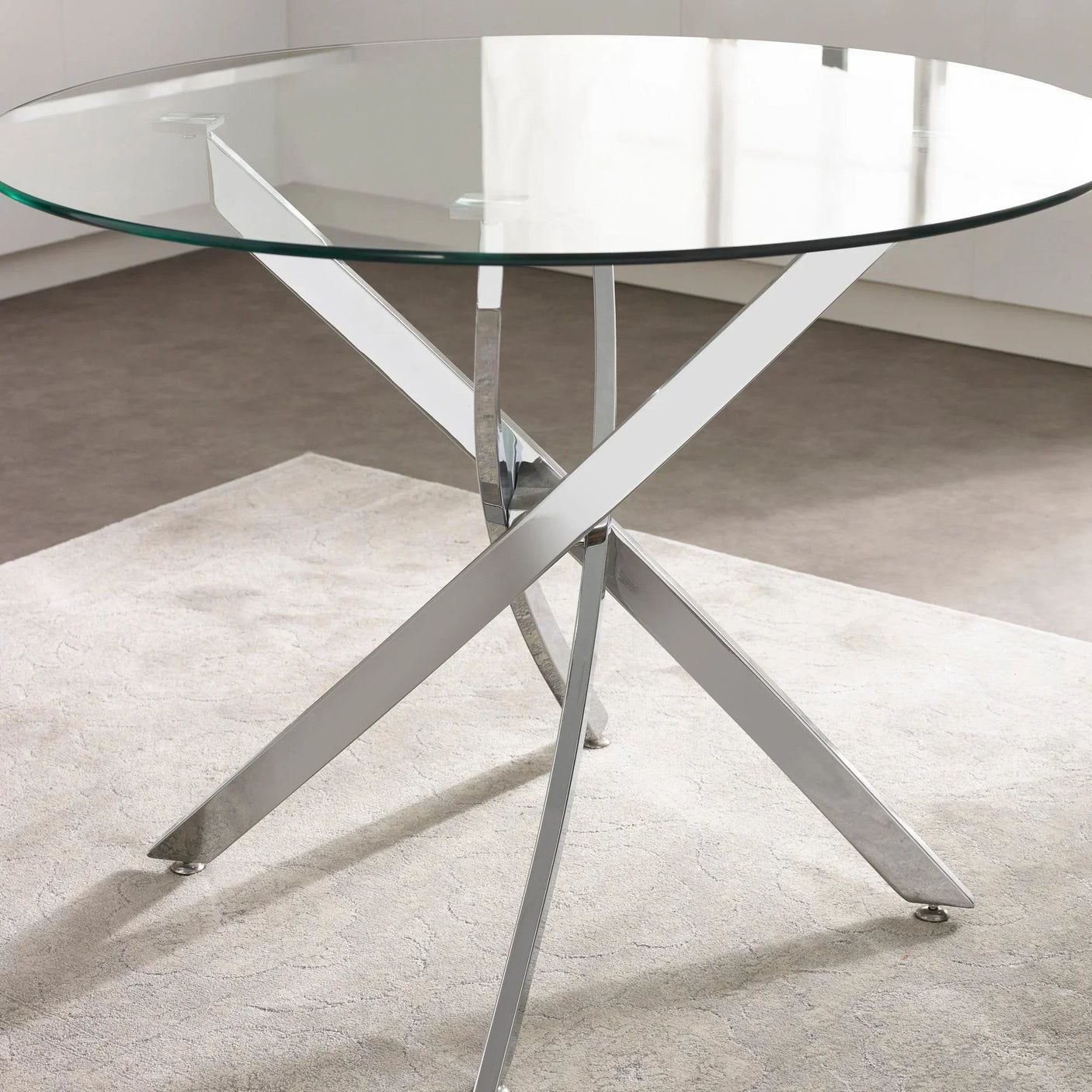 Round glass dining table with crossed chrome legs on a light rug