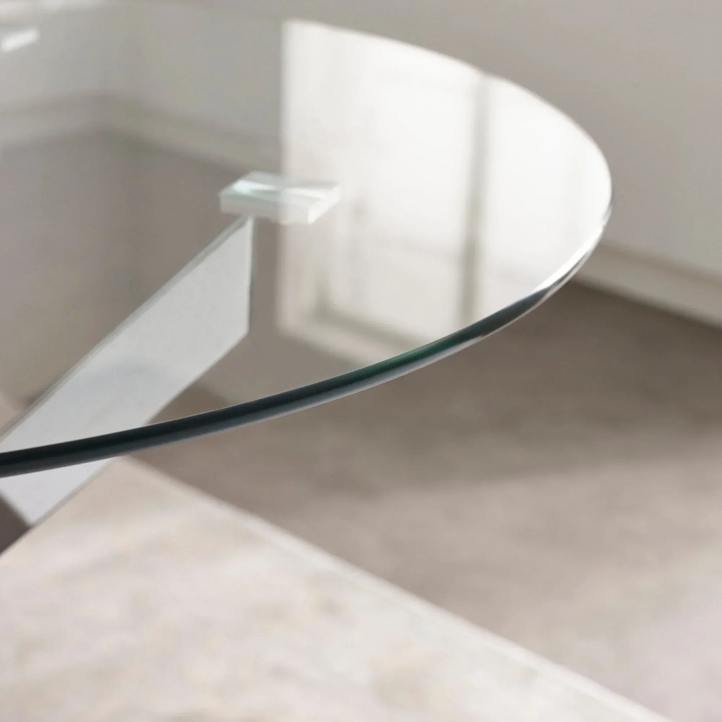 Closeup of round glass dining table edge with metal leg and transparent top