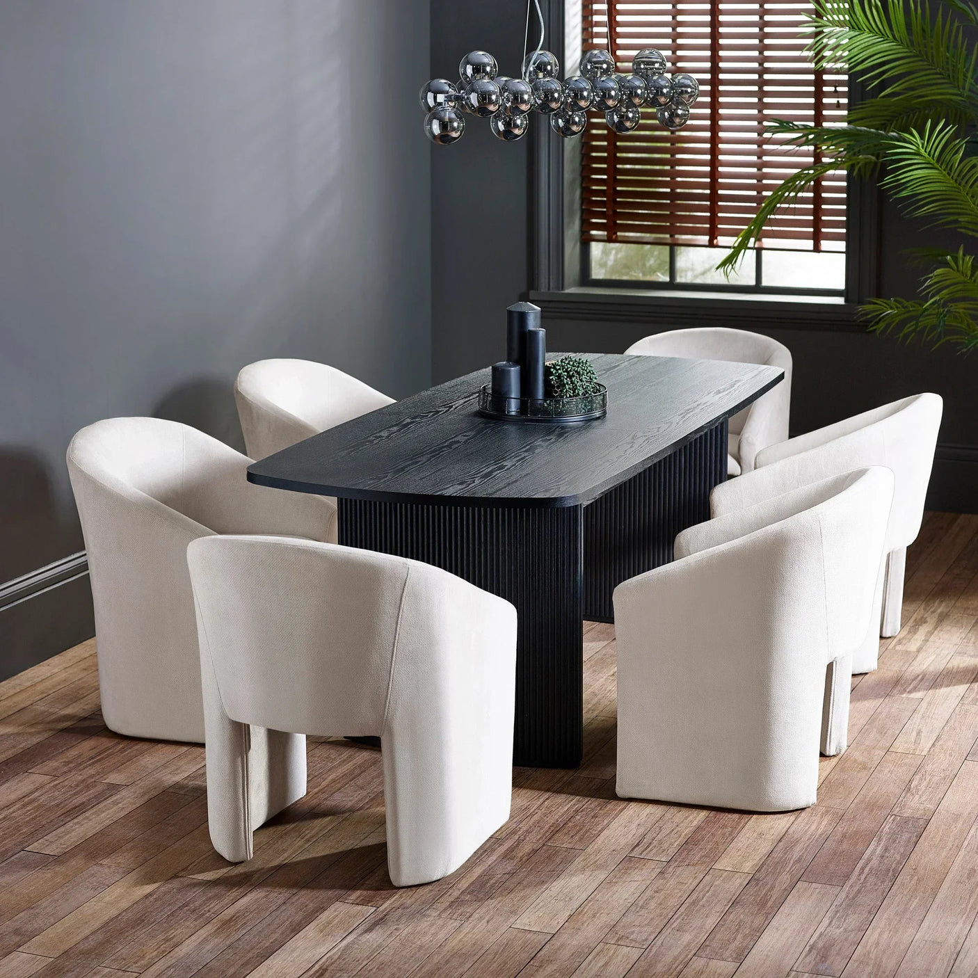 Black wood dining table with six cream velvet chairs in modern dining room
