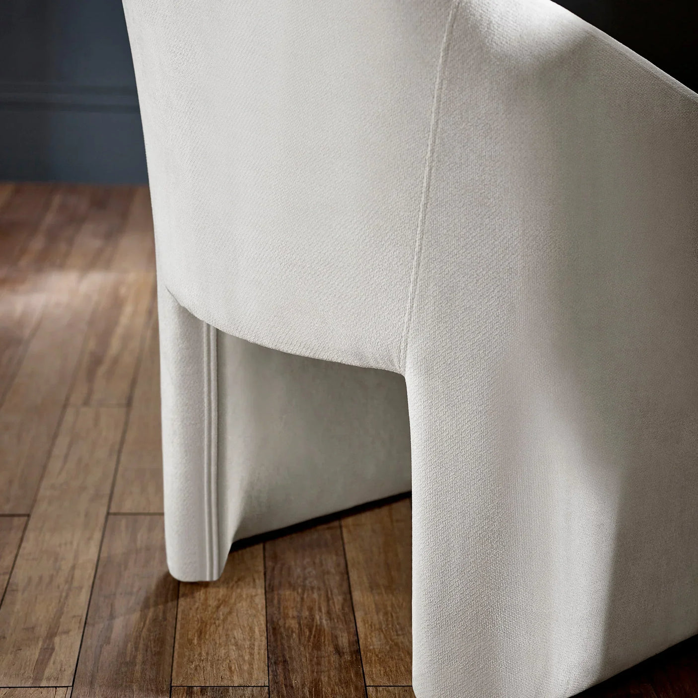 Ivory upholstered dining chair with skirt detail on wooden floor