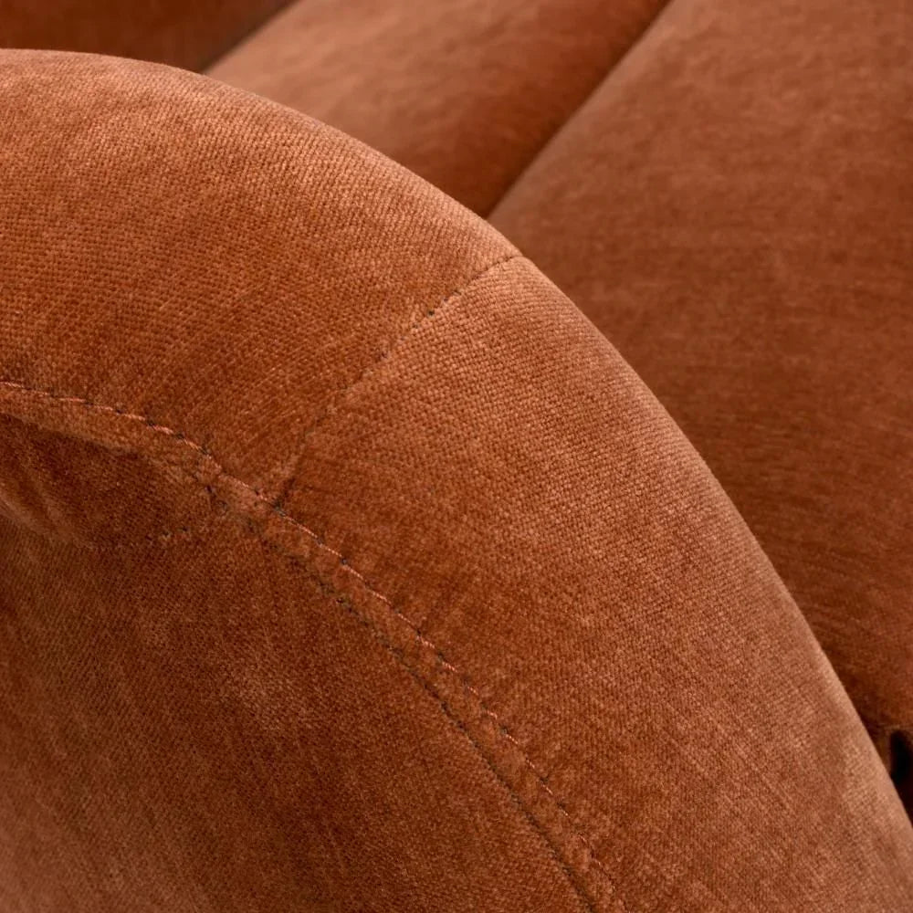 Closeup of rust velvet sofa armrest with visible stitching detail