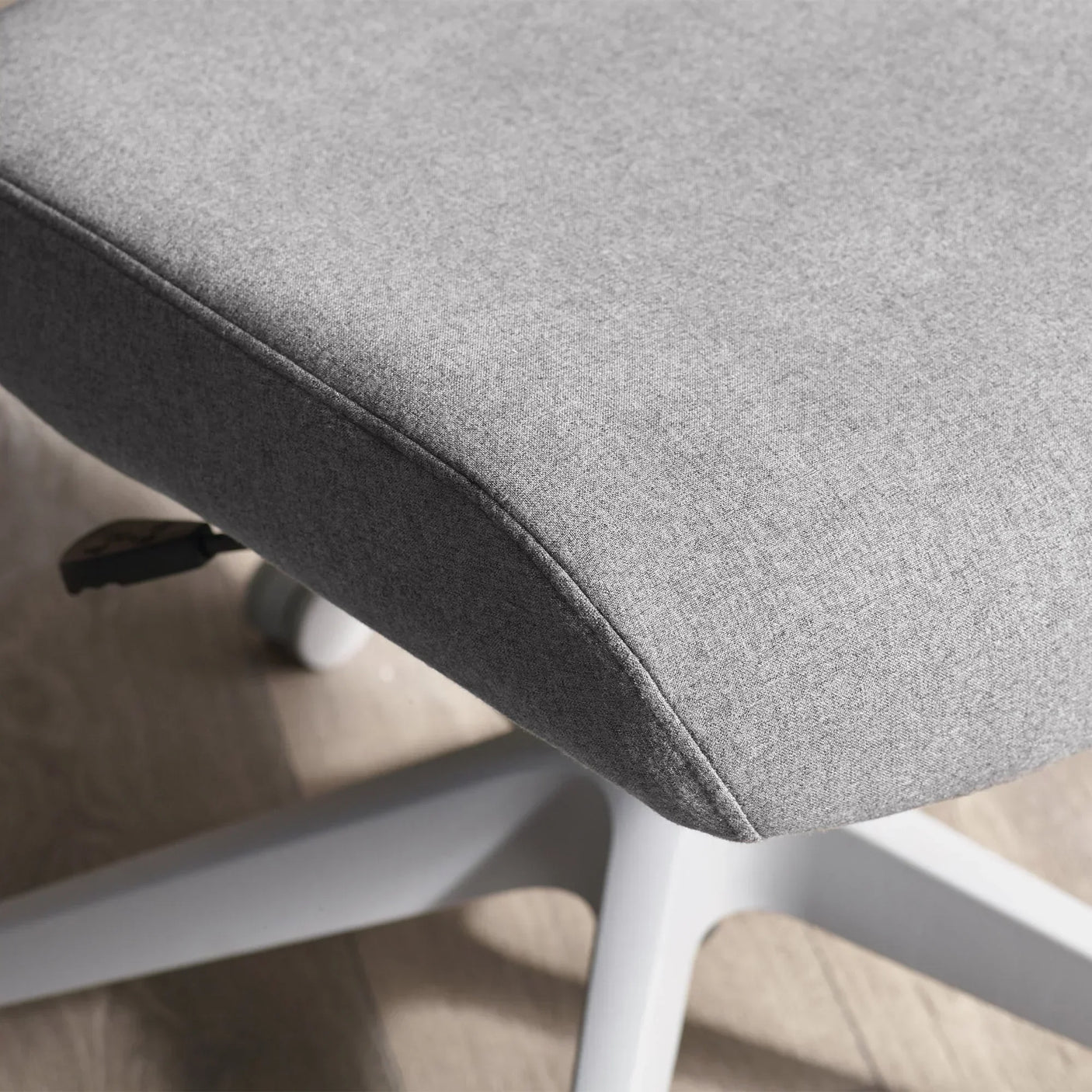 Grey fabric office chair seat detail with white base on wooden floor