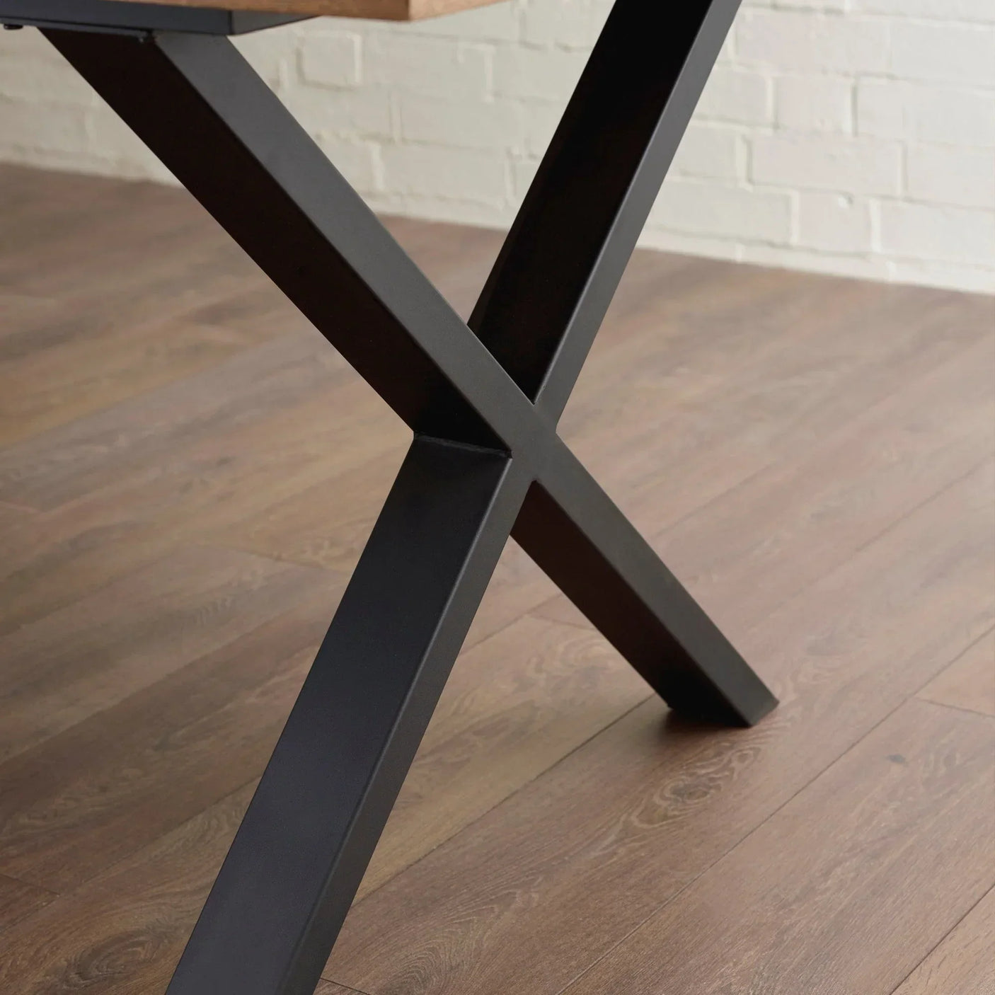 Black metal dining table leg with X-frame on wood floor