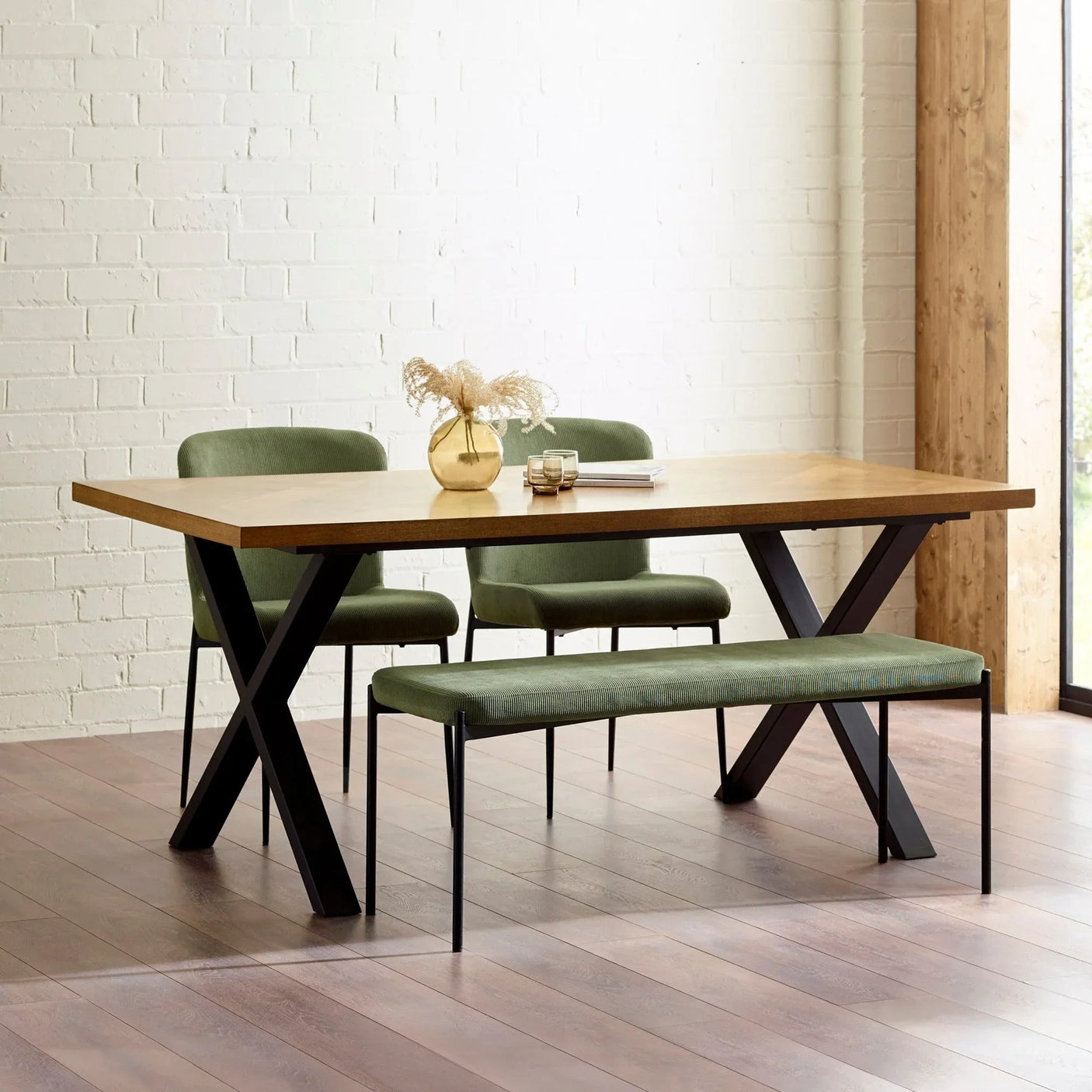 Dining table set with wooden top, black metal legs, green bench and chairs on wood floor