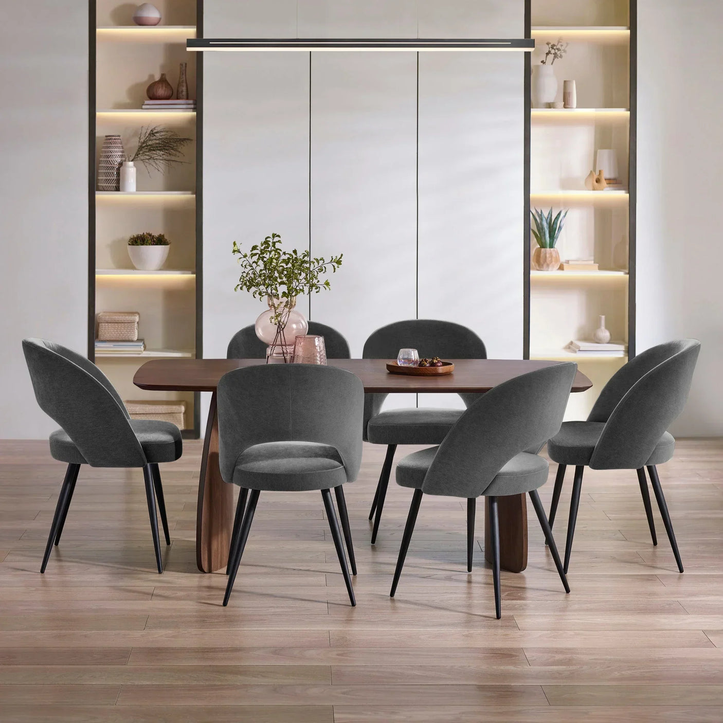 Grey velvet dining chairs with black legs around a wooden dining table in modern room