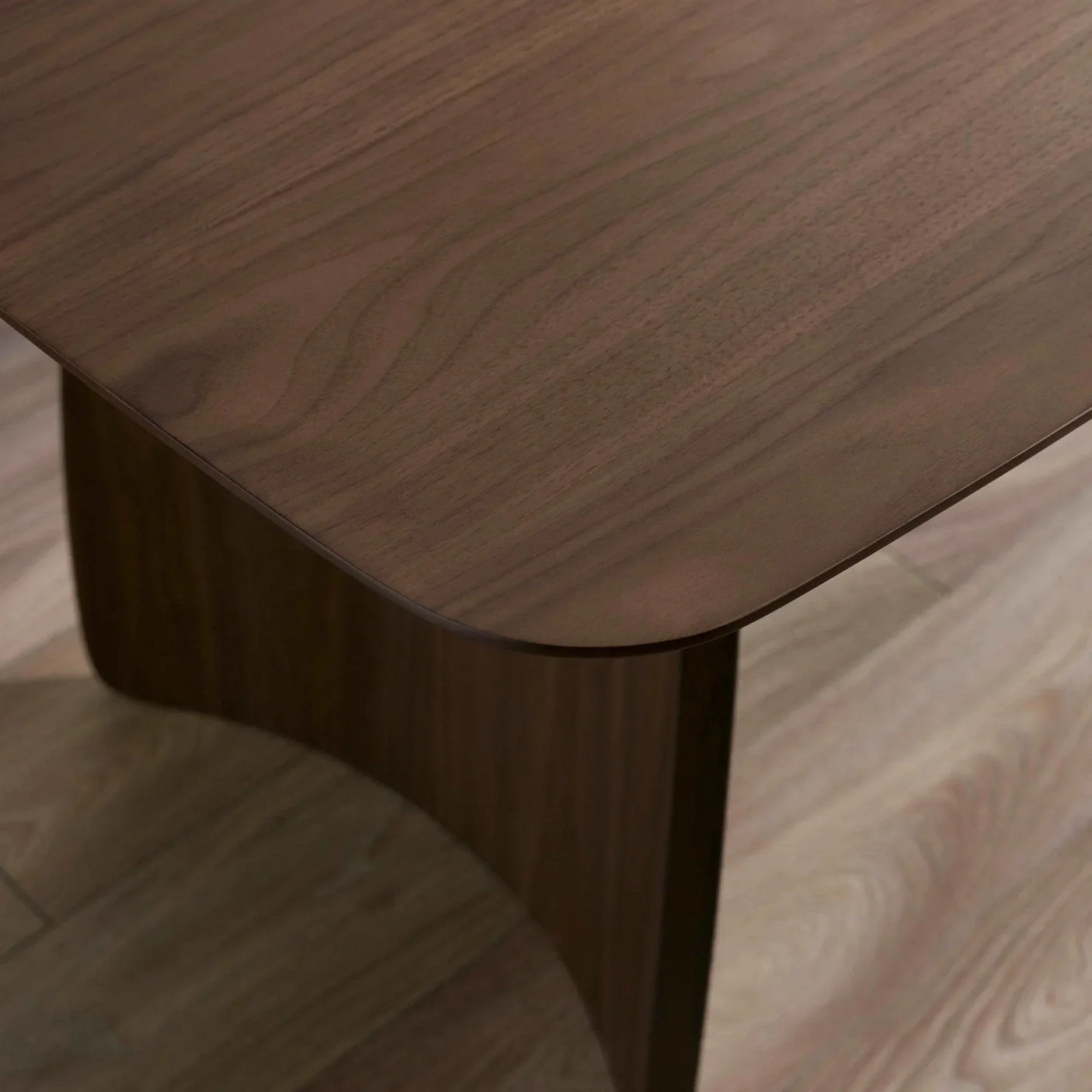 Close view of walnut wood dining table corner with curved edge on wood floor