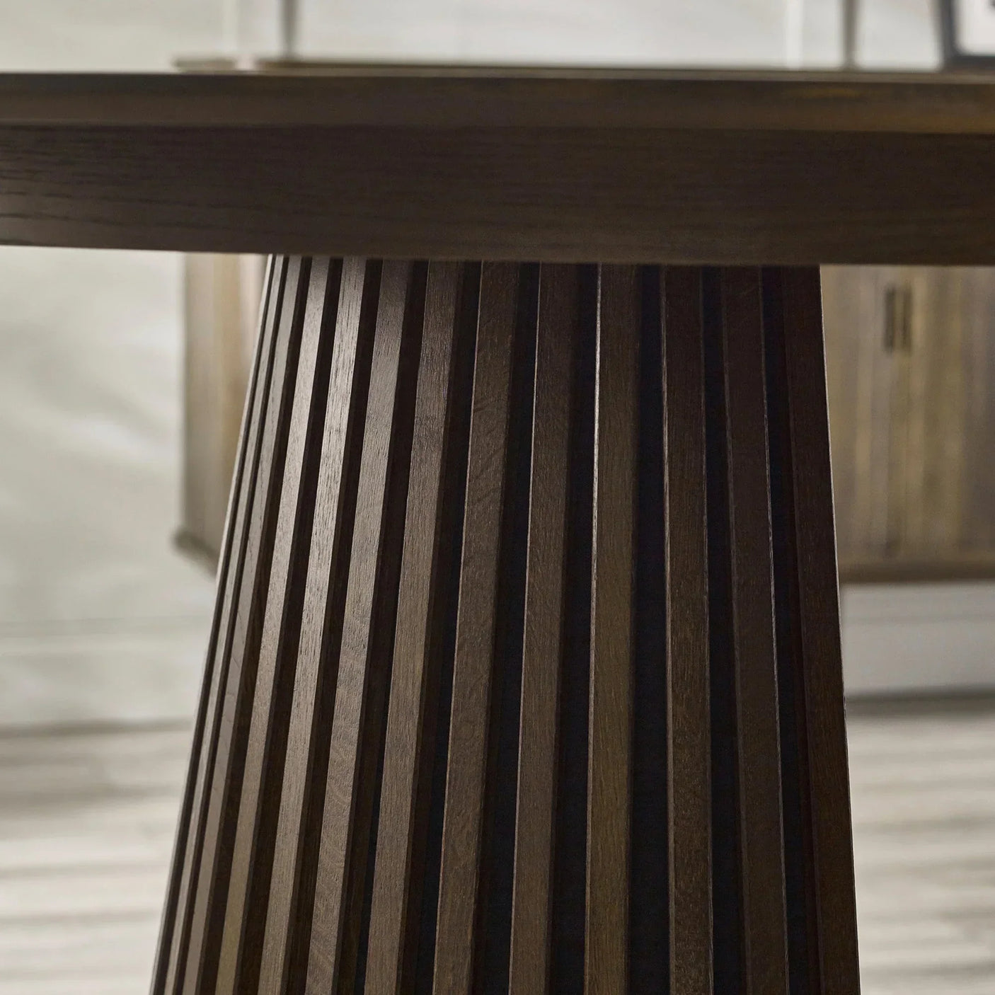 Dark wood dining table with fluted pedestal base and vertical slat detail