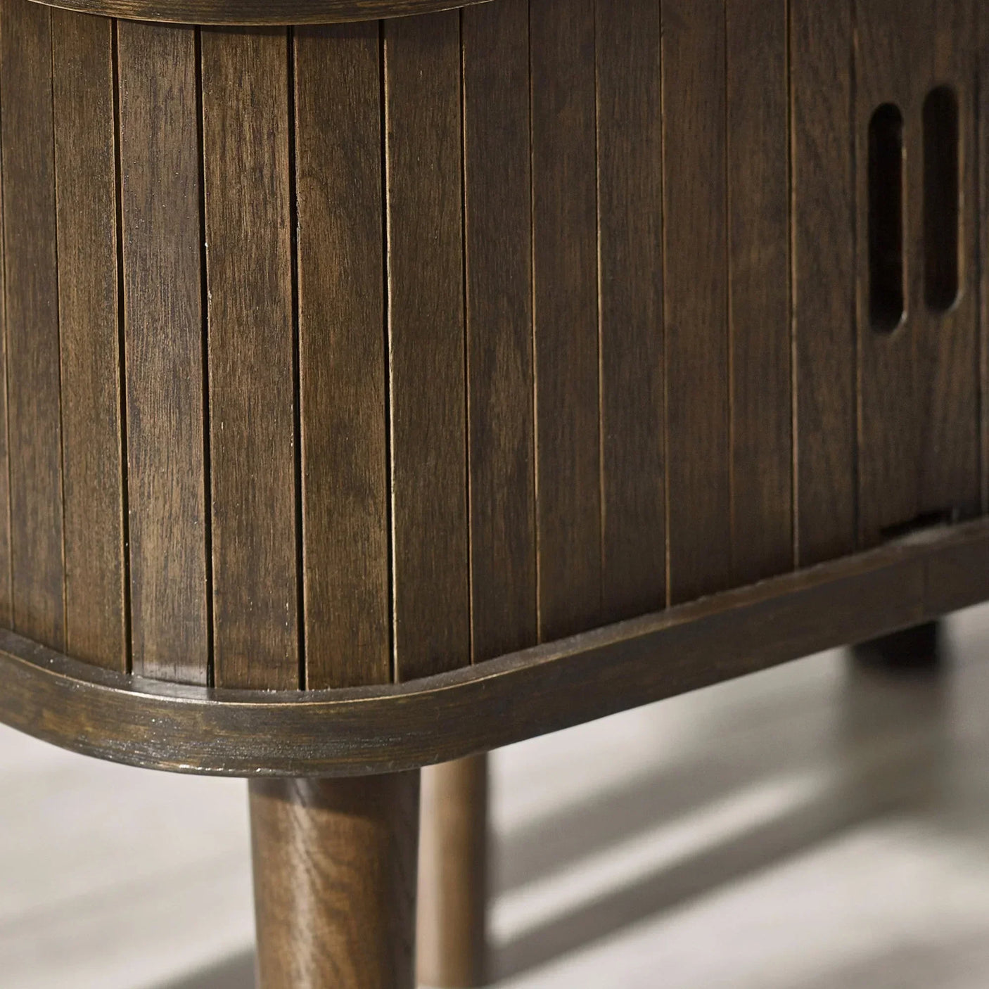 Closeup of wooden sideboard leg and slatted cabinet detail with brown finish