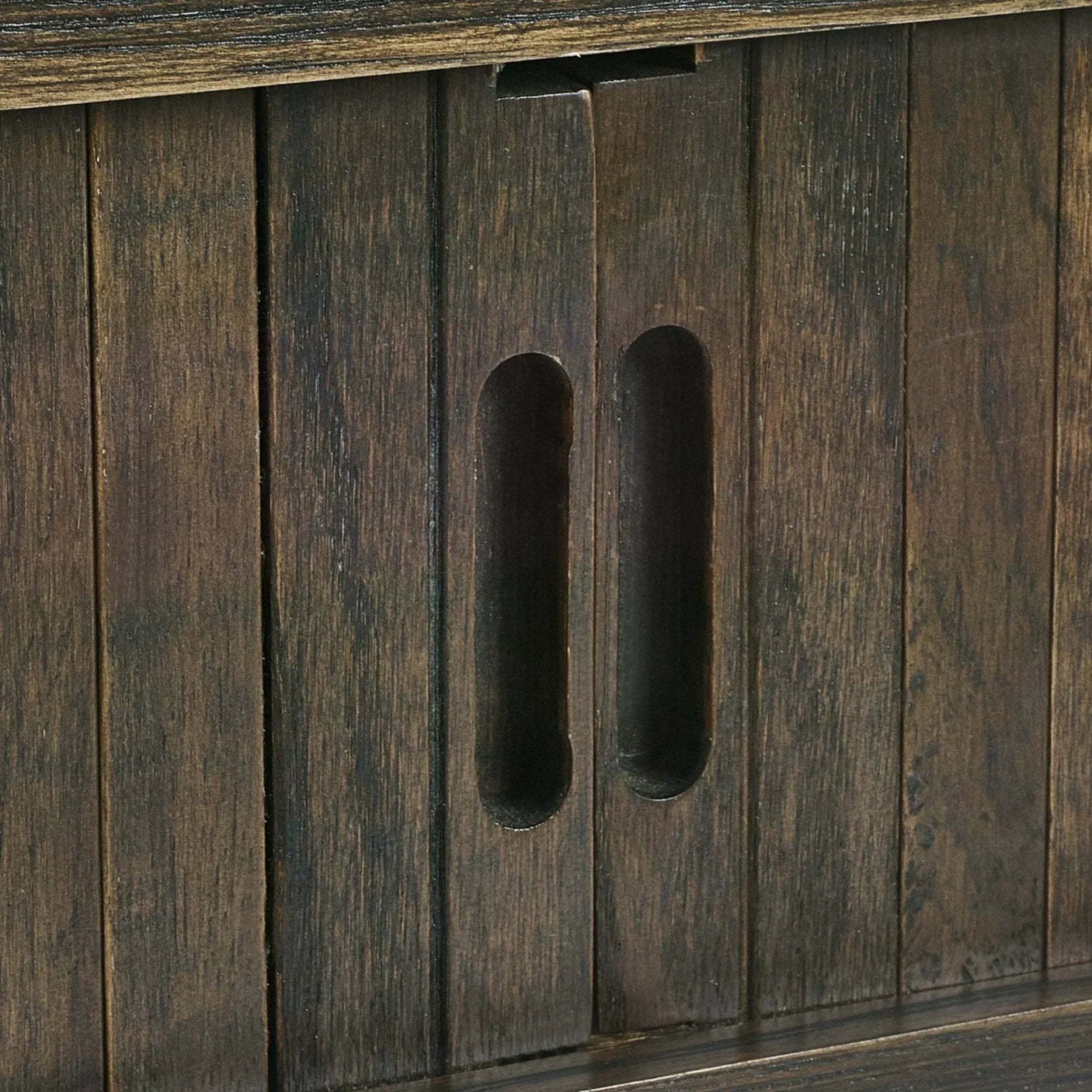 Closeup of wooden sideboard cabinet doors with integrated handles and dark wood finish