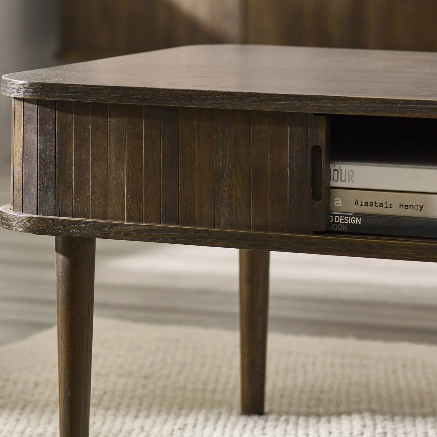 Dark wood coffee table with sliding door storage and open shelving on a cream rug