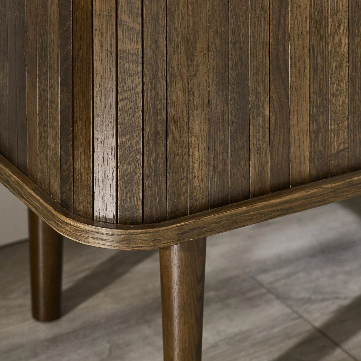 Close-up of dark wood furniture leg and fluted panel detailing on laminate flooring