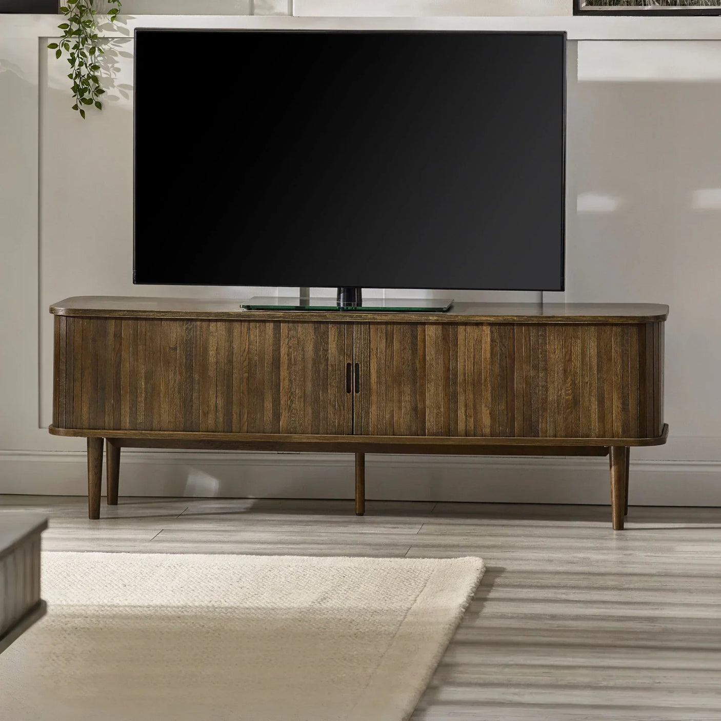 Walnut TV unit with vertical slat doors and splayed legs in a modern living room