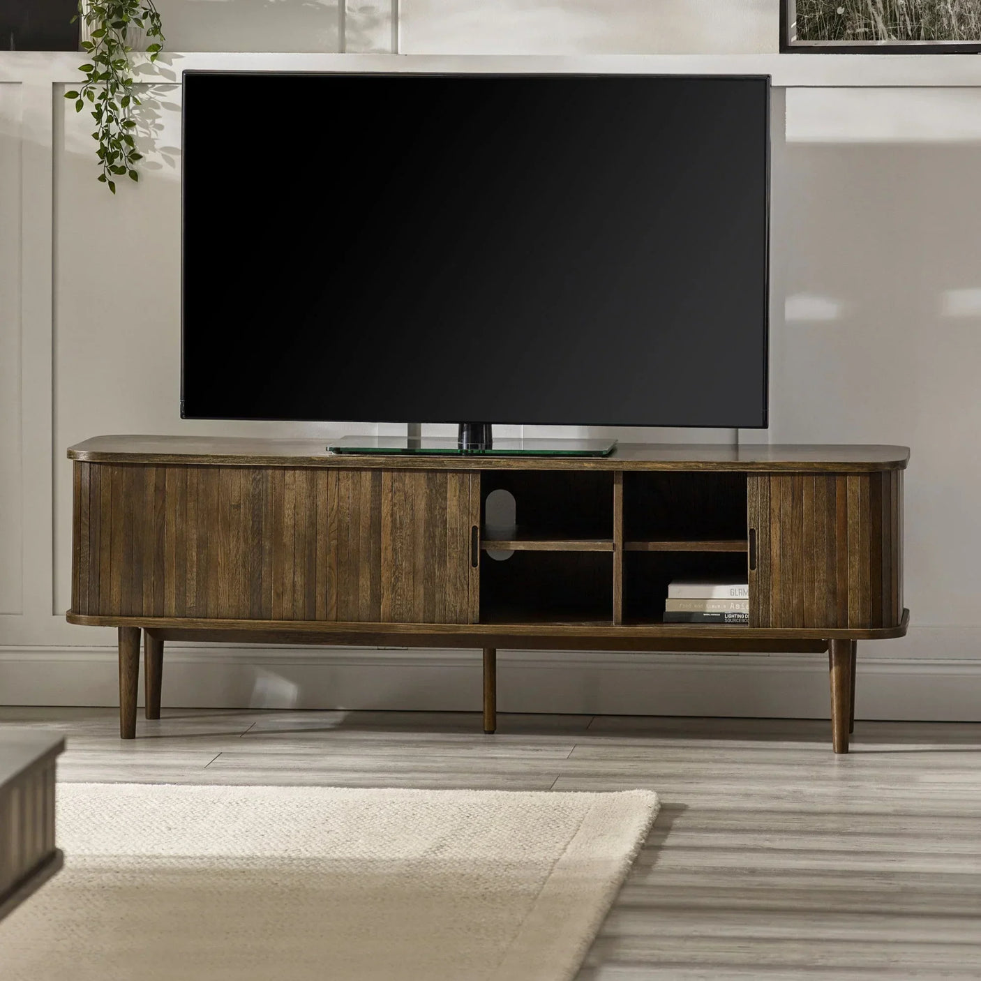 Wooden TV unit with sliding doors and open shelves in living room setting