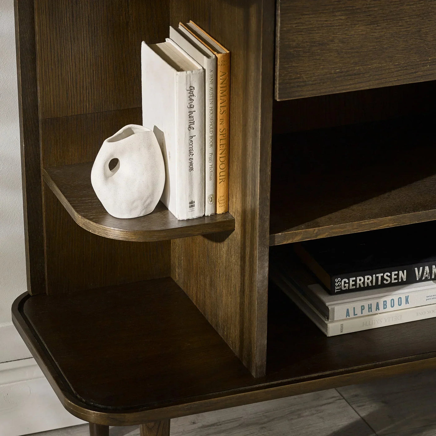 Dark wood bookcase shelf with books and ceramic vase accessory