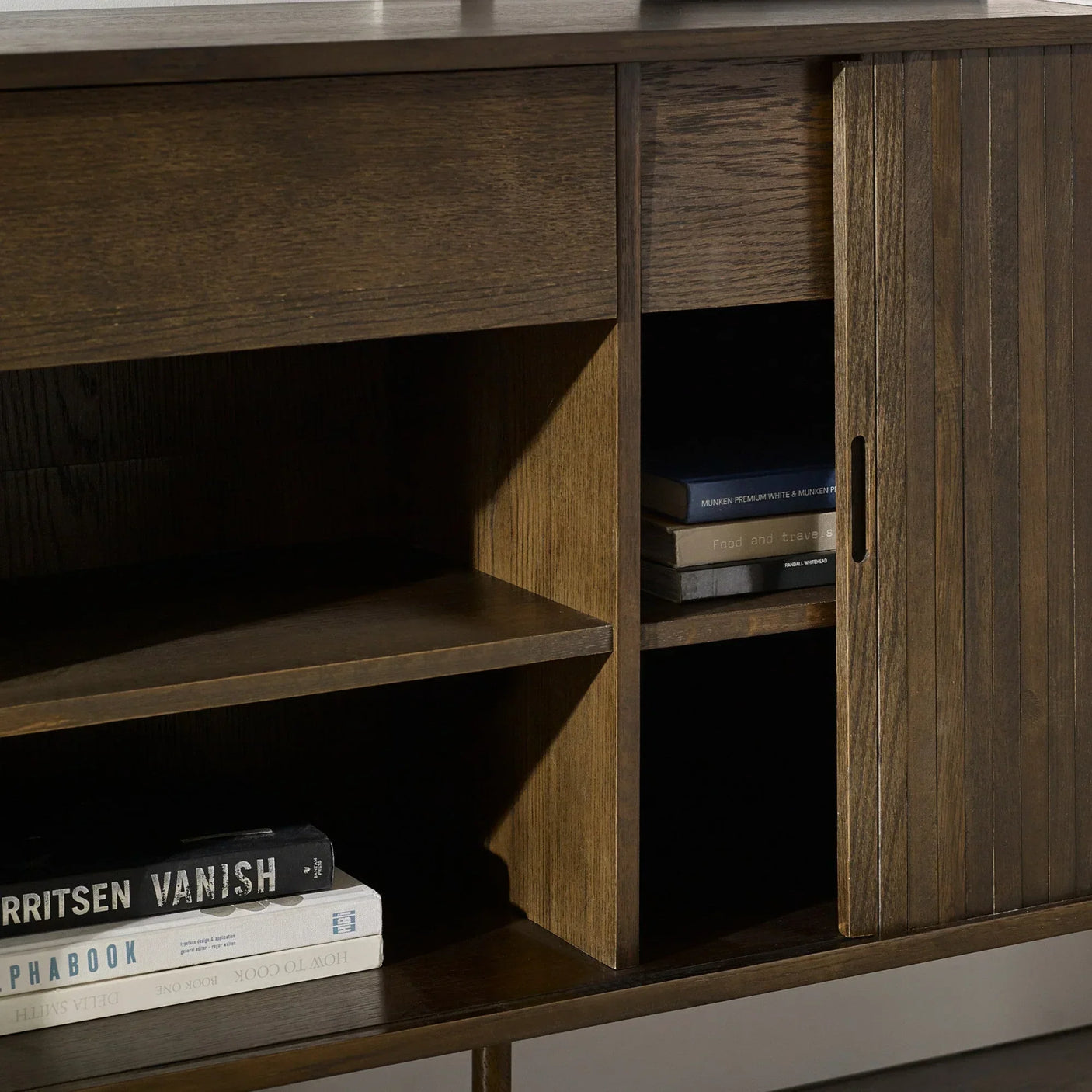 Dark wood sideboard with open shelving and sliding grooved door, books on lower shelf