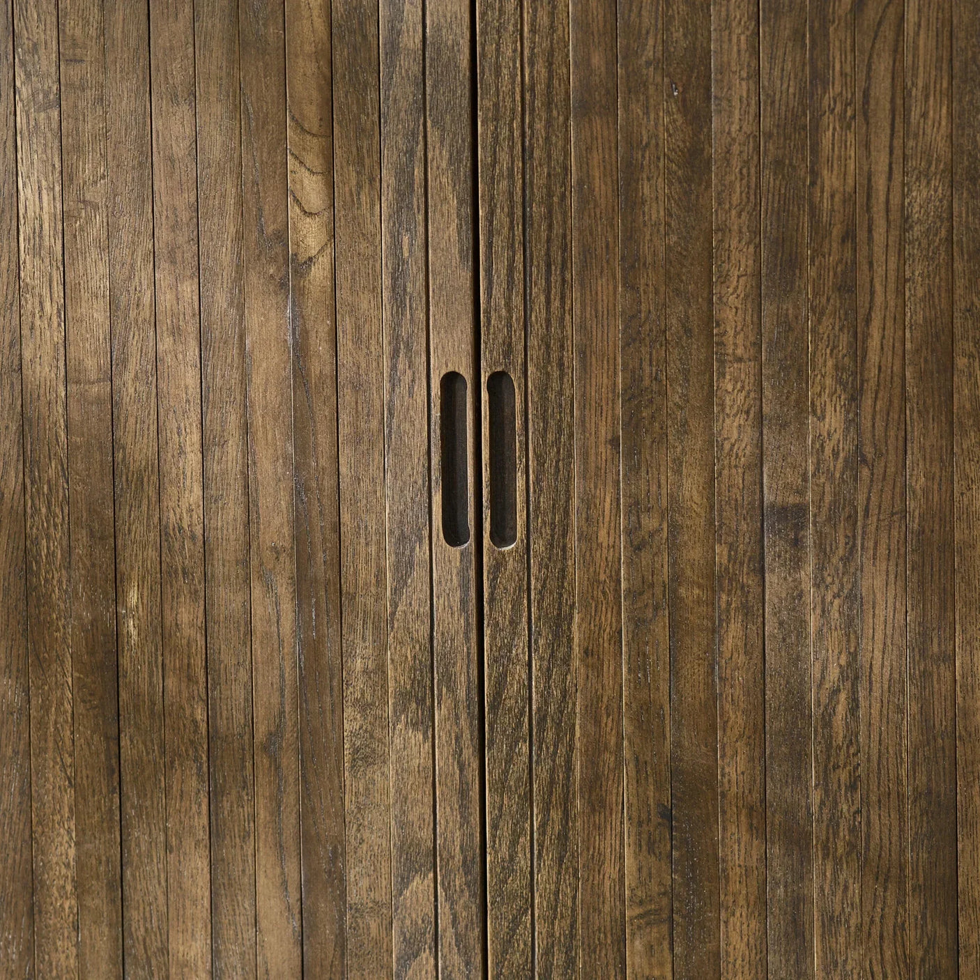 Closeup of wooden cabinet doors with vertical slats and cutout handles