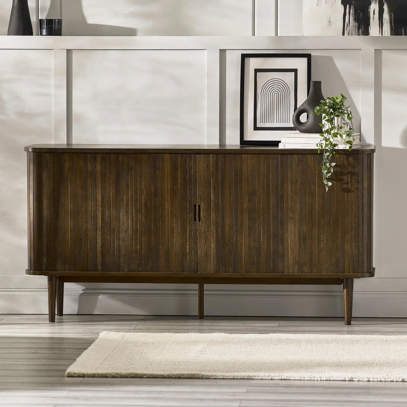 Dark wood sideboard with vertical panel doors, styled with vase, framed print and trailing plant