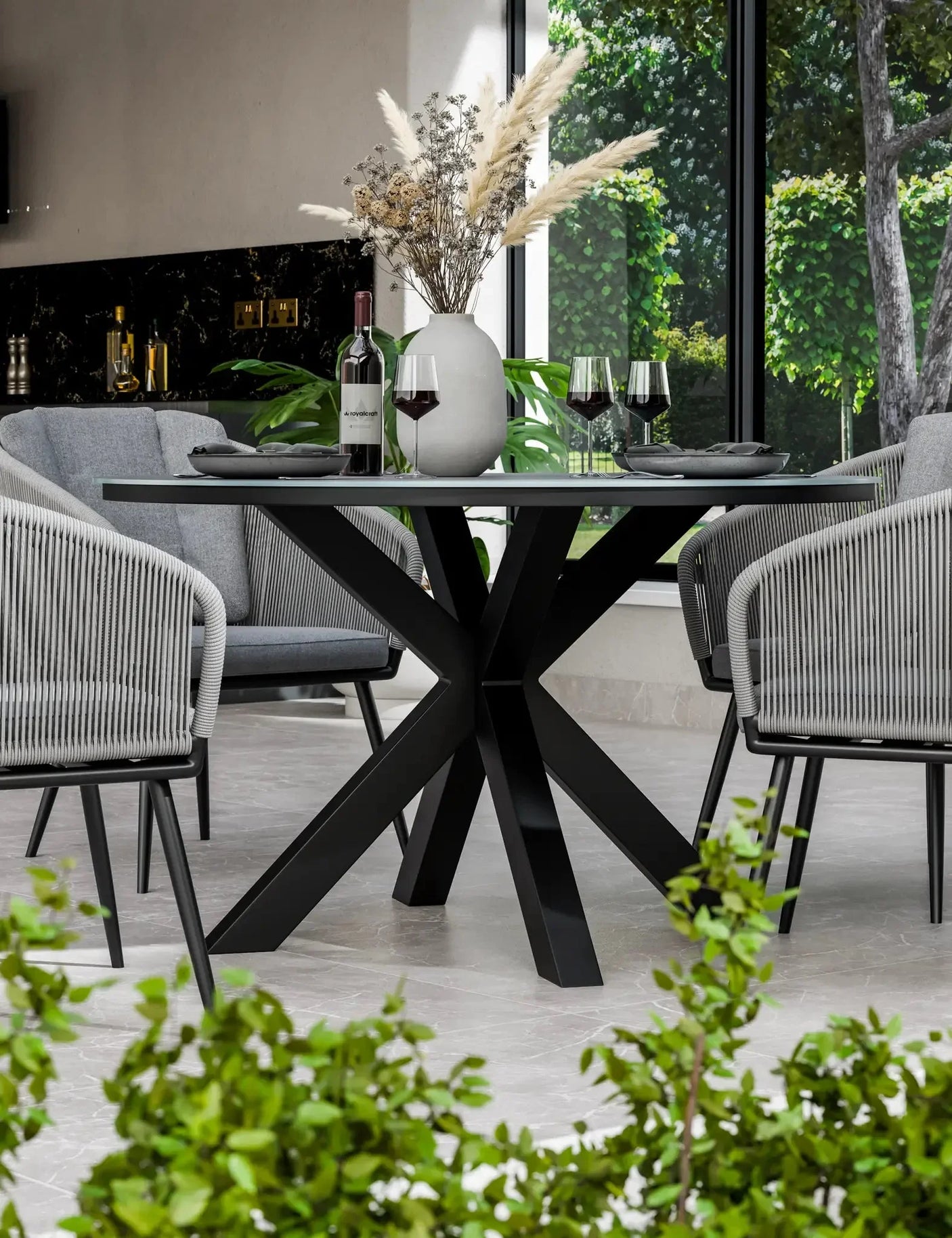 Modern black dining table with glass top, grey chairs, and decorative vase indoors