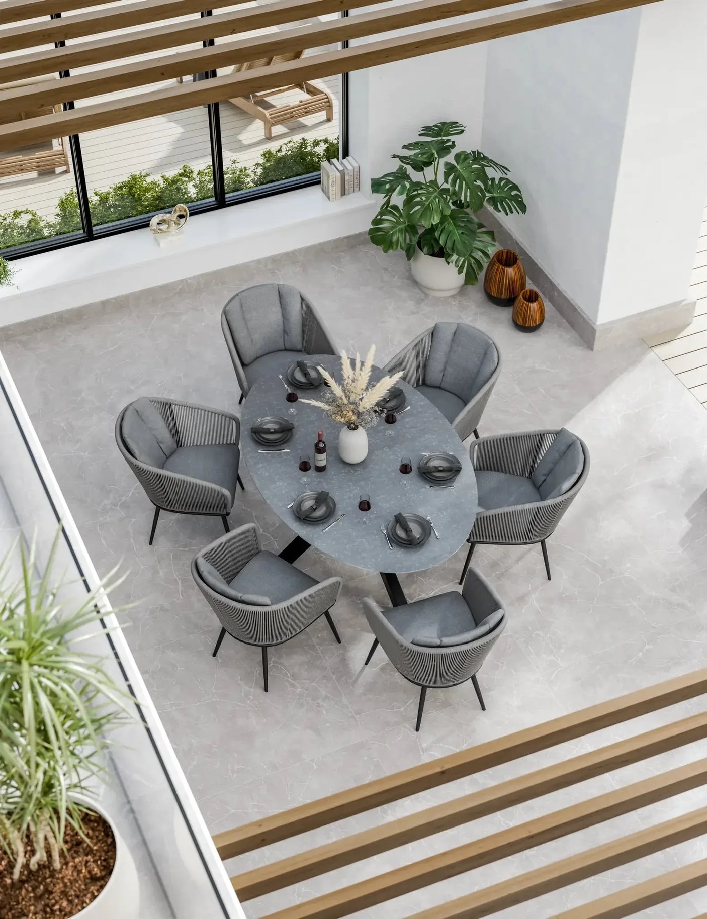 Grey oval dining table with six grey velvet chairs in modern bright dining room