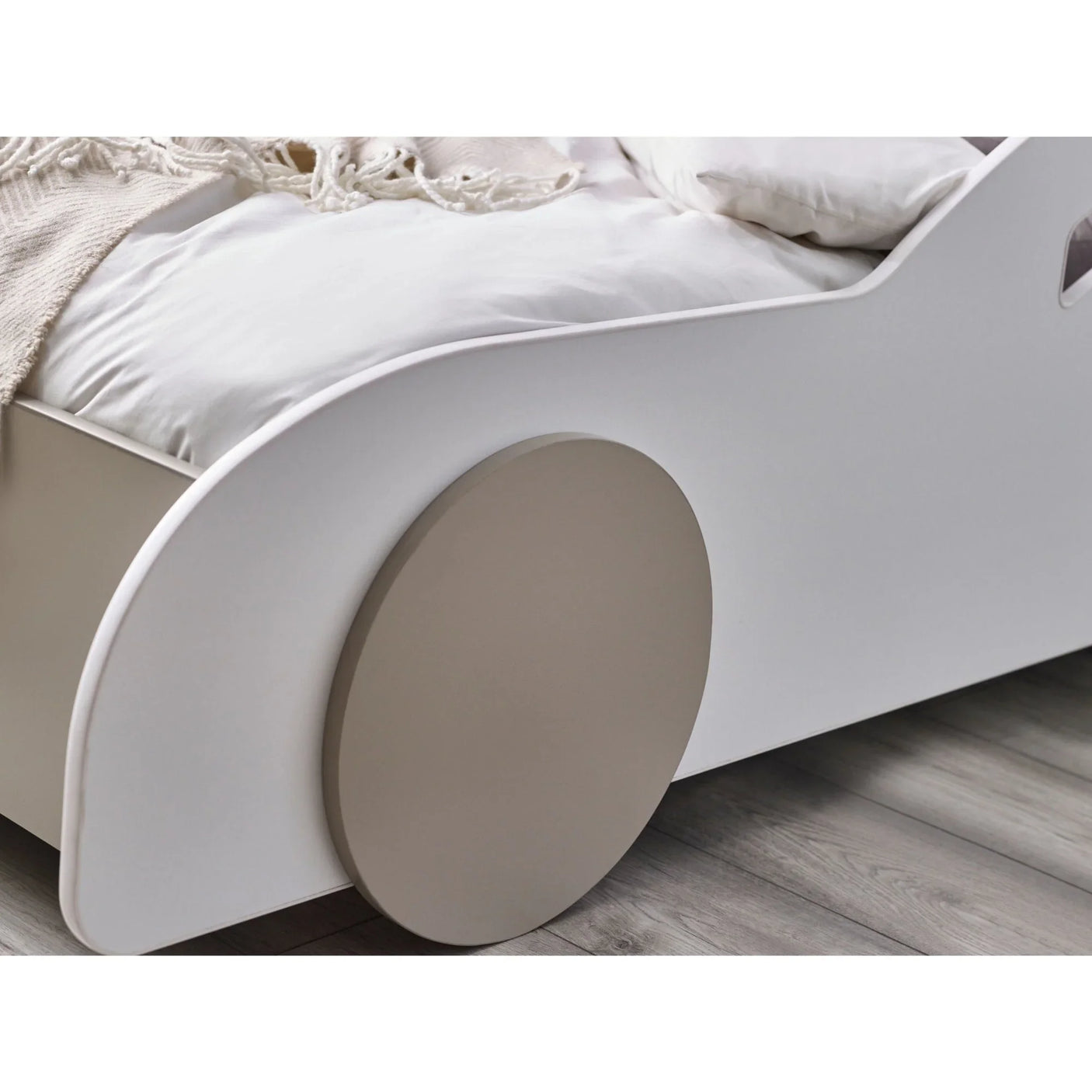 White wooden kids bed with beige wheel detail on grey wood floor